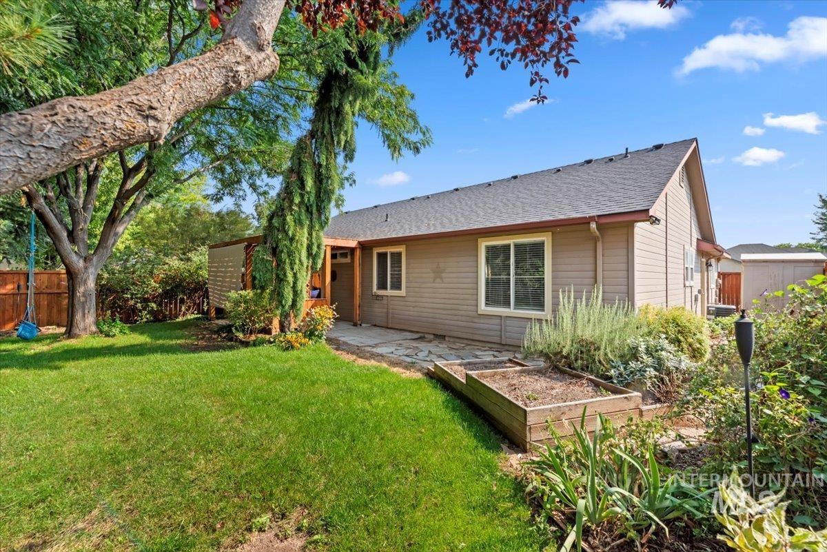 Rear view of house with a patio area, a vegetable garden, and roof with shingles