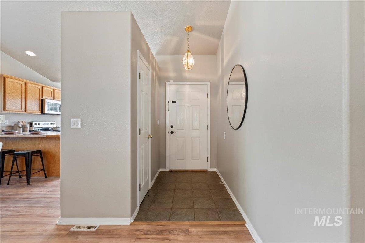 Corridor featuring light wood-style floors, lofted ceiling, recessed lighting, and a textured ceiling