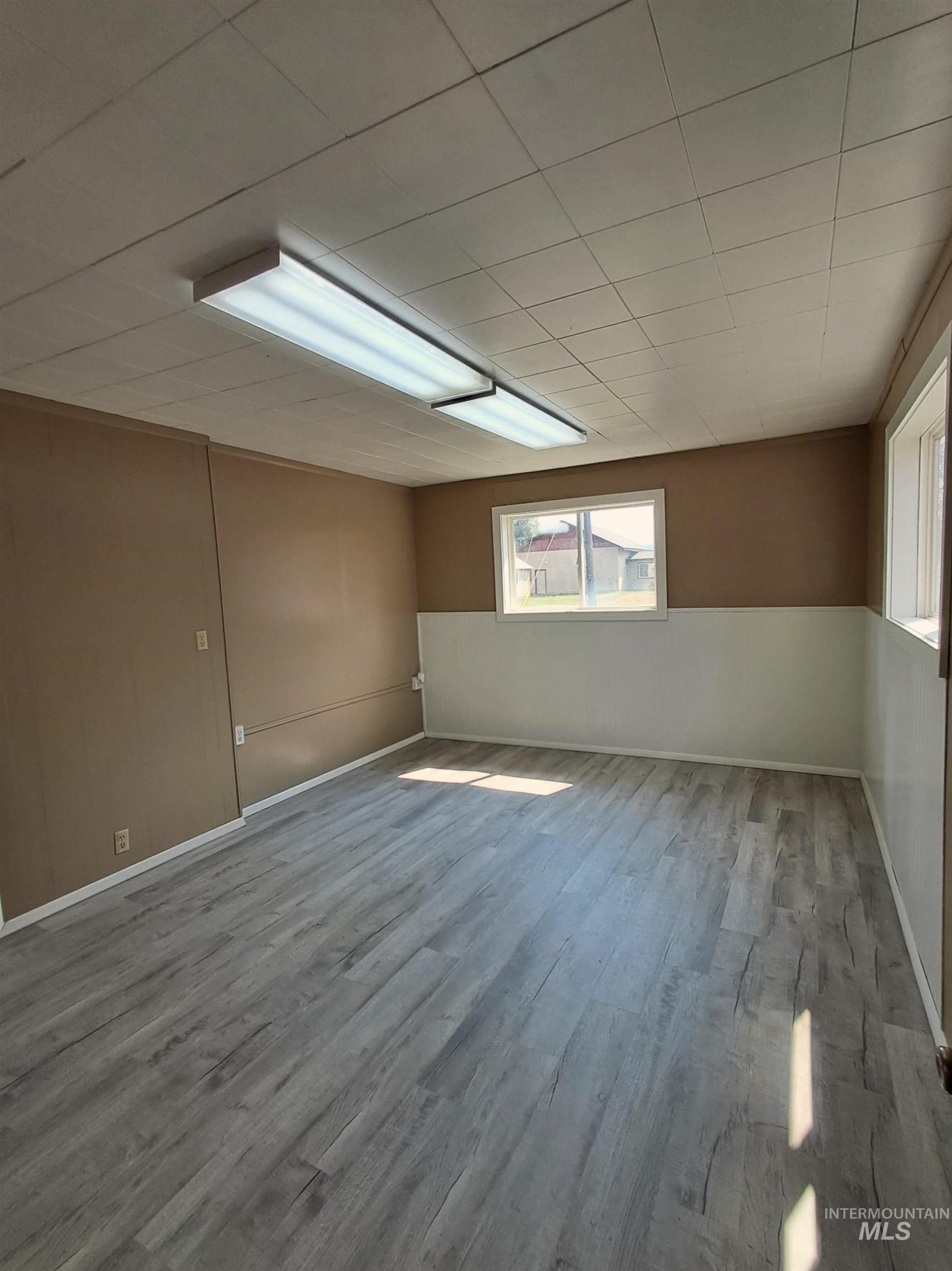 Unfurnished room with wood finished floors and a wainscoted wall