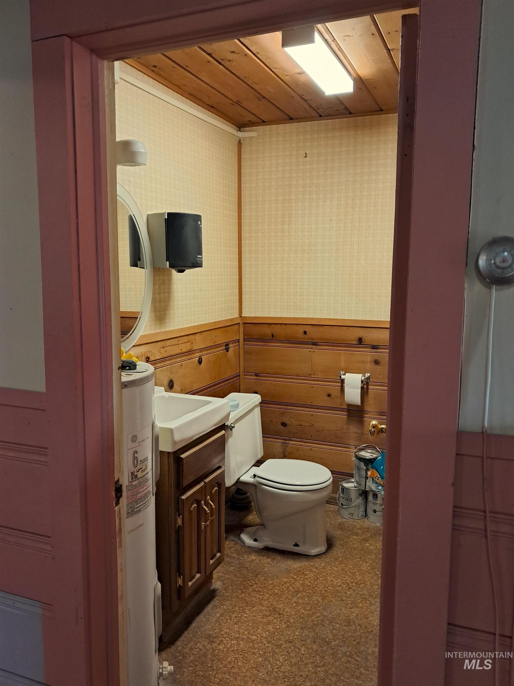 Bathroom featuring vanity, wooden ceiling, water heater, and wallpapered walls