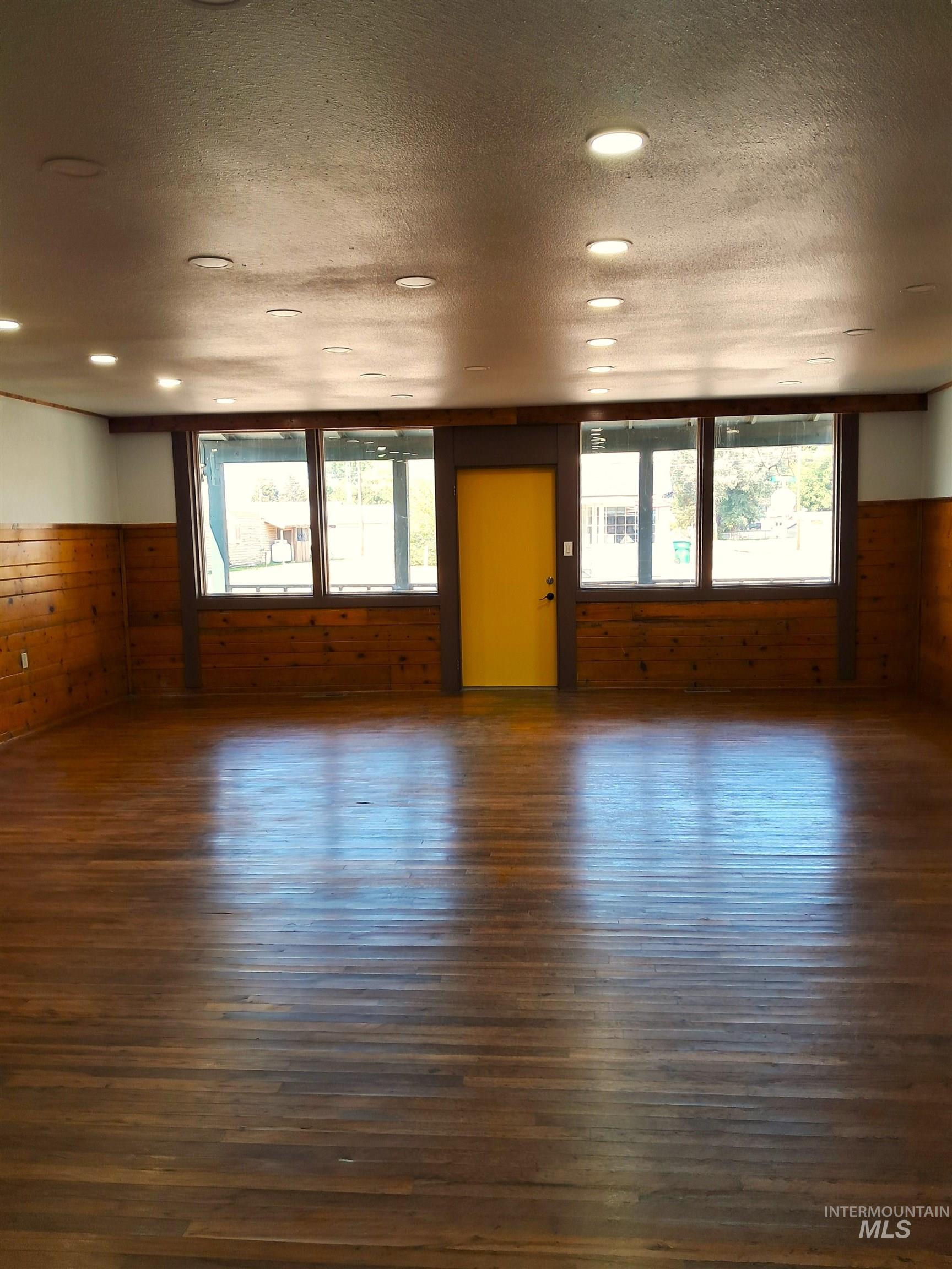 Unfurnished room featuring dark wood-style flooring, wooden walls, and a textured ceiling