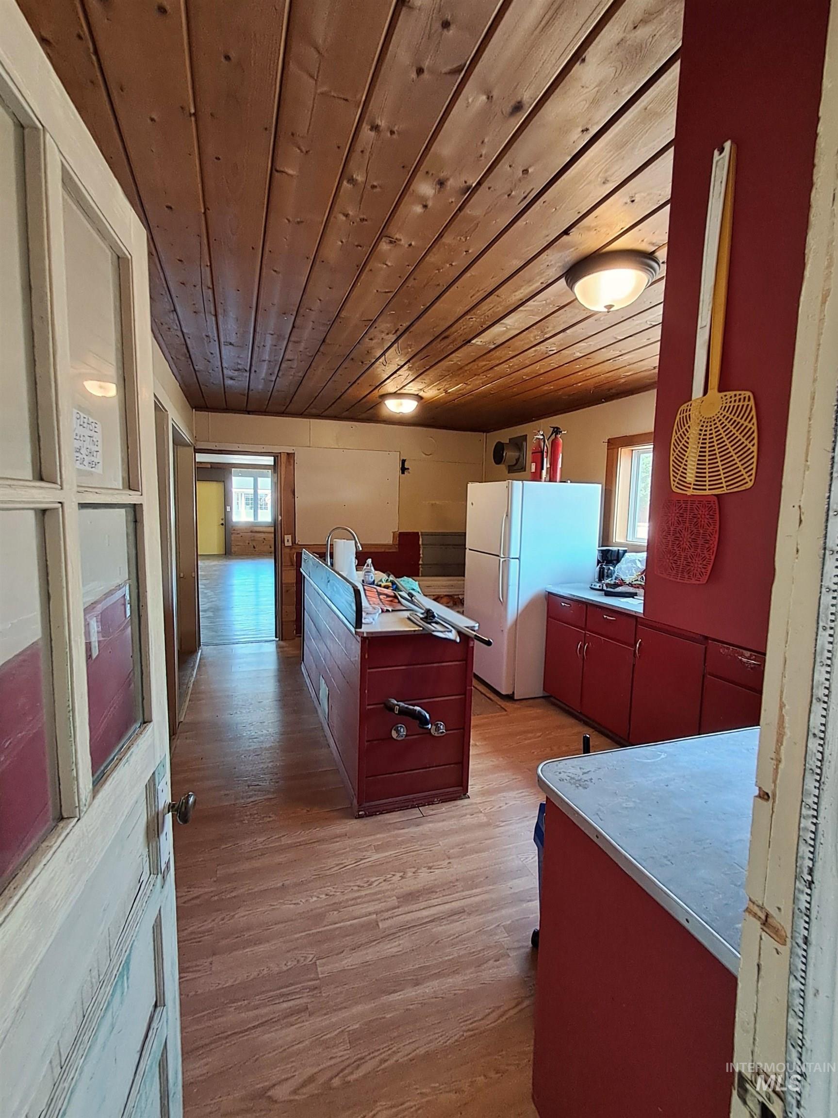Kitchen featuring wooden ceiling, light wood-type flooring, freestanding refrigerator, light countertops, and a center island