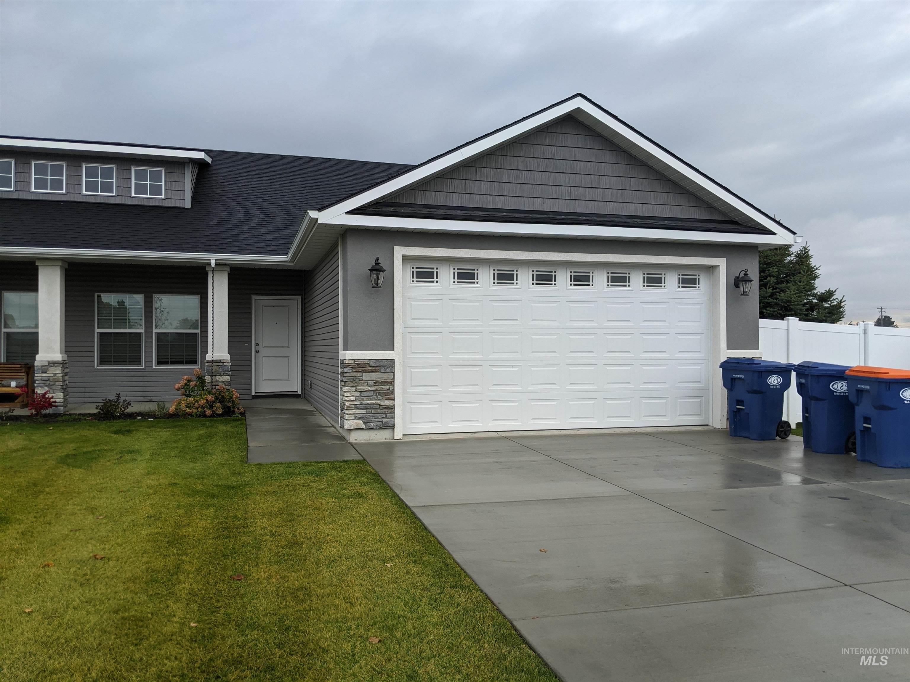 Craftsman-style house featuring stone siding, driveway, an attached garage, and a shingled roof