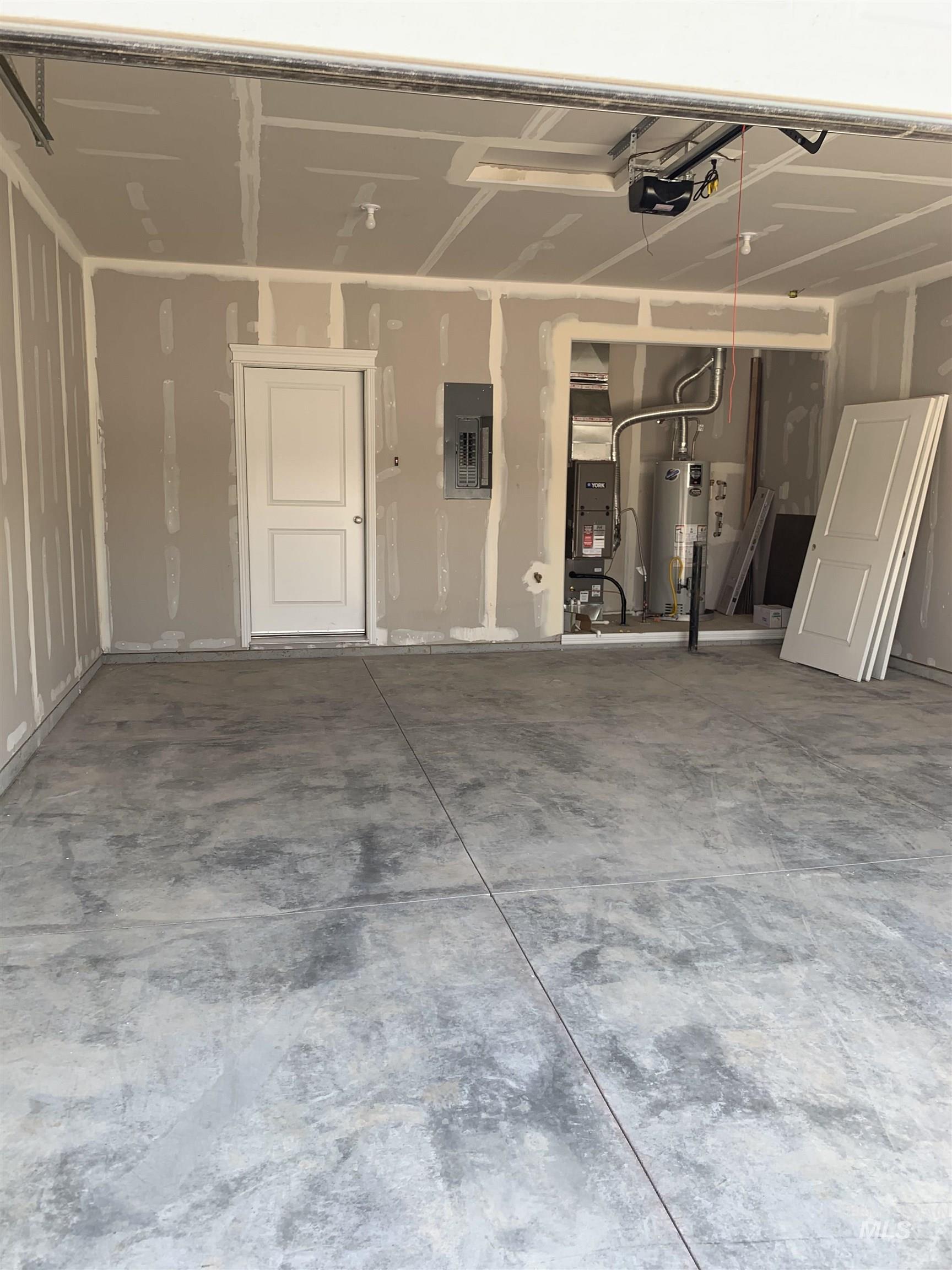 Garage with electric panel, water heater, and a garage door opener
