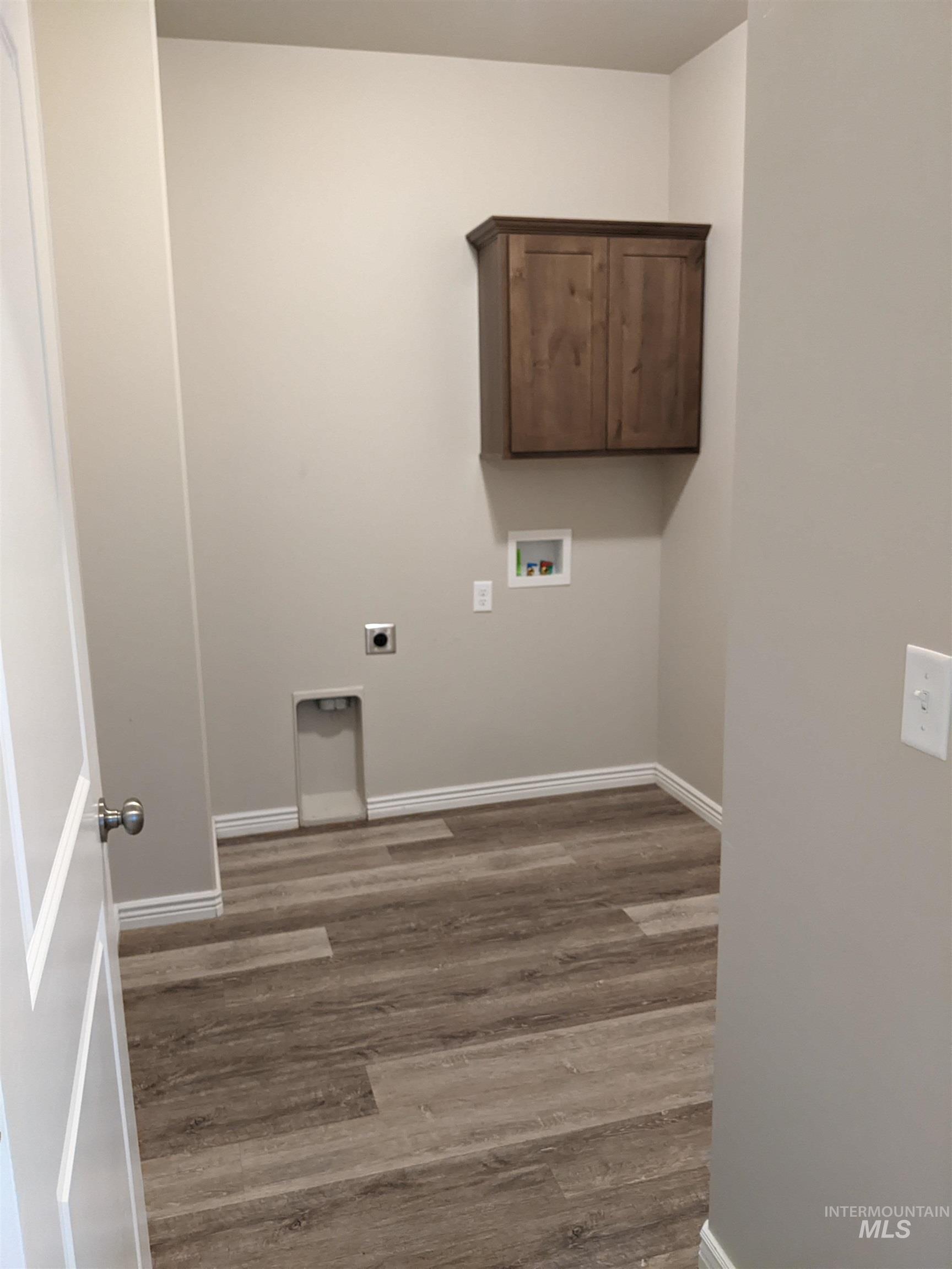 Laundry area with electric dryer hookup, light wood-type flooring, hookup for a washing machine, and cabinet space
