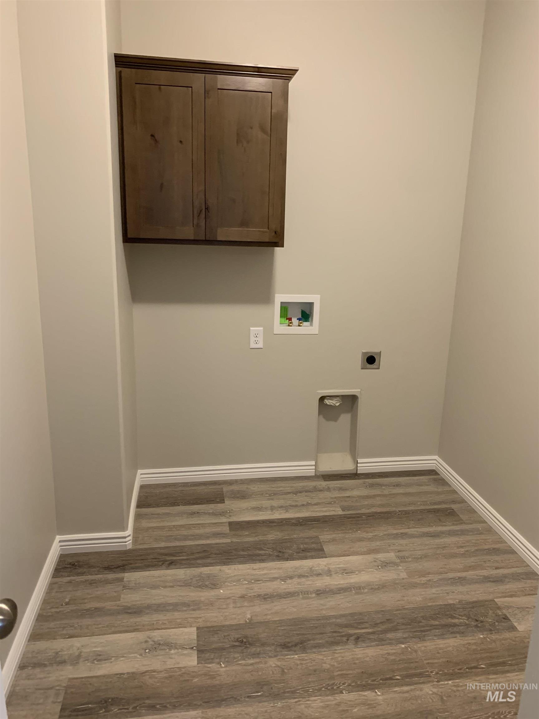 Laundry area with hookup for an electric dryer, dark wood-style flooring, hookup for a washing machine, and cabinet space