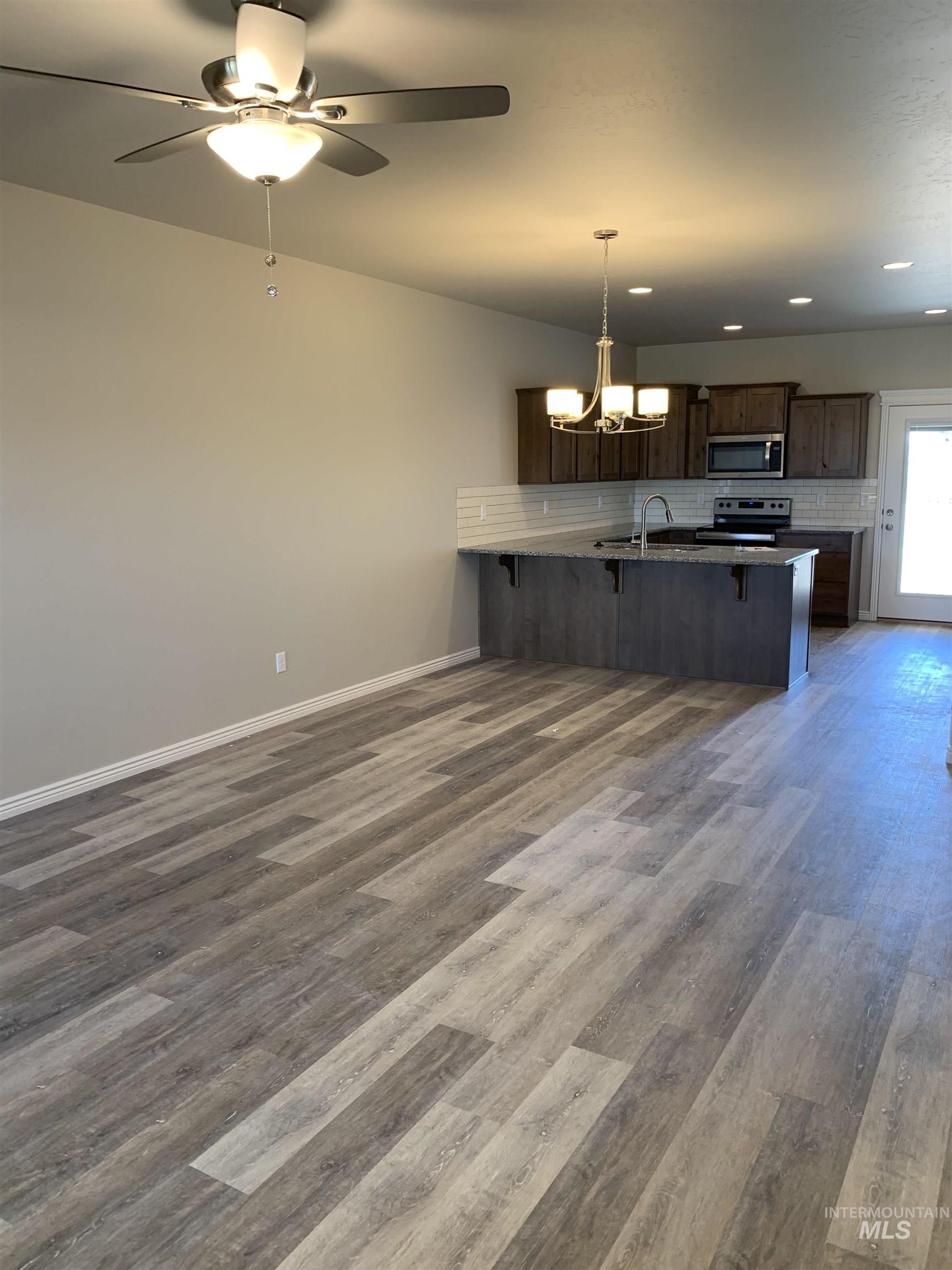 Kitchen with a kitchen breakfast bar, dark brown cabinetry, a chandelier, dark wood finished floors, and recessed lighting