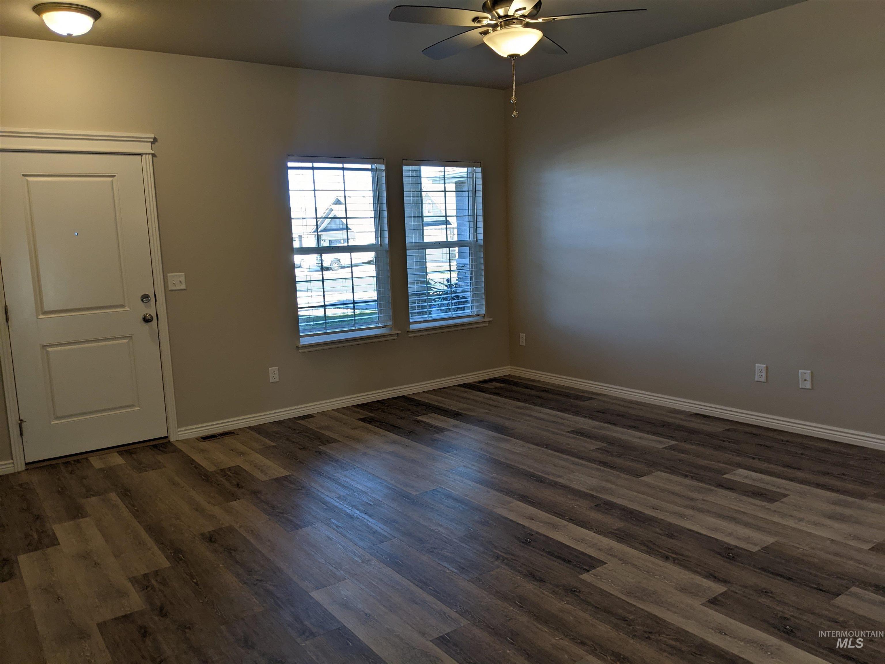 Unfurnished room with dark wood-style flooring and a ceiling fan