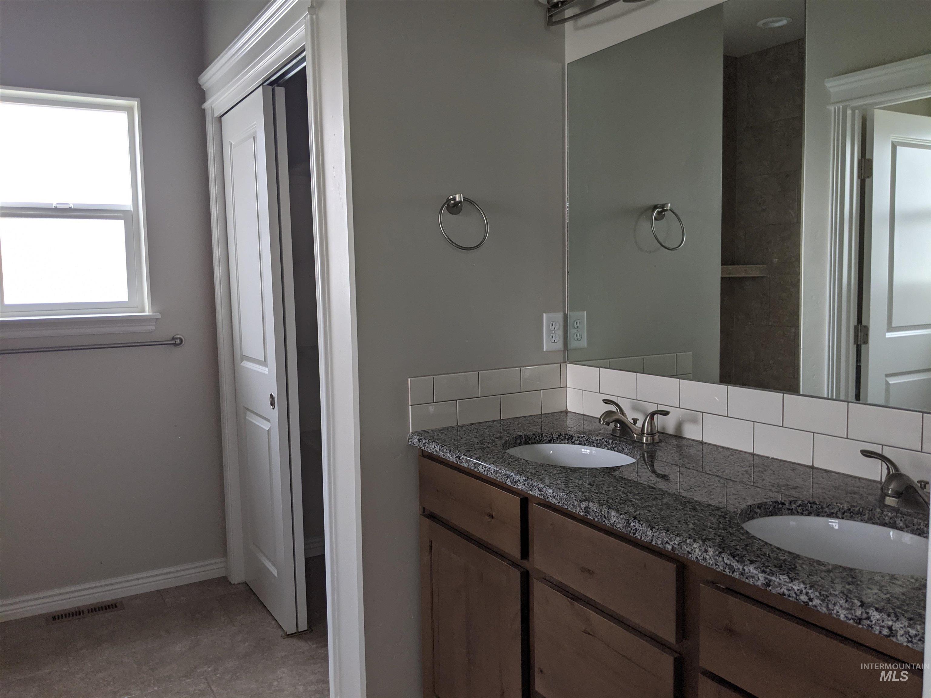 Full bath with double vanity and baseboards