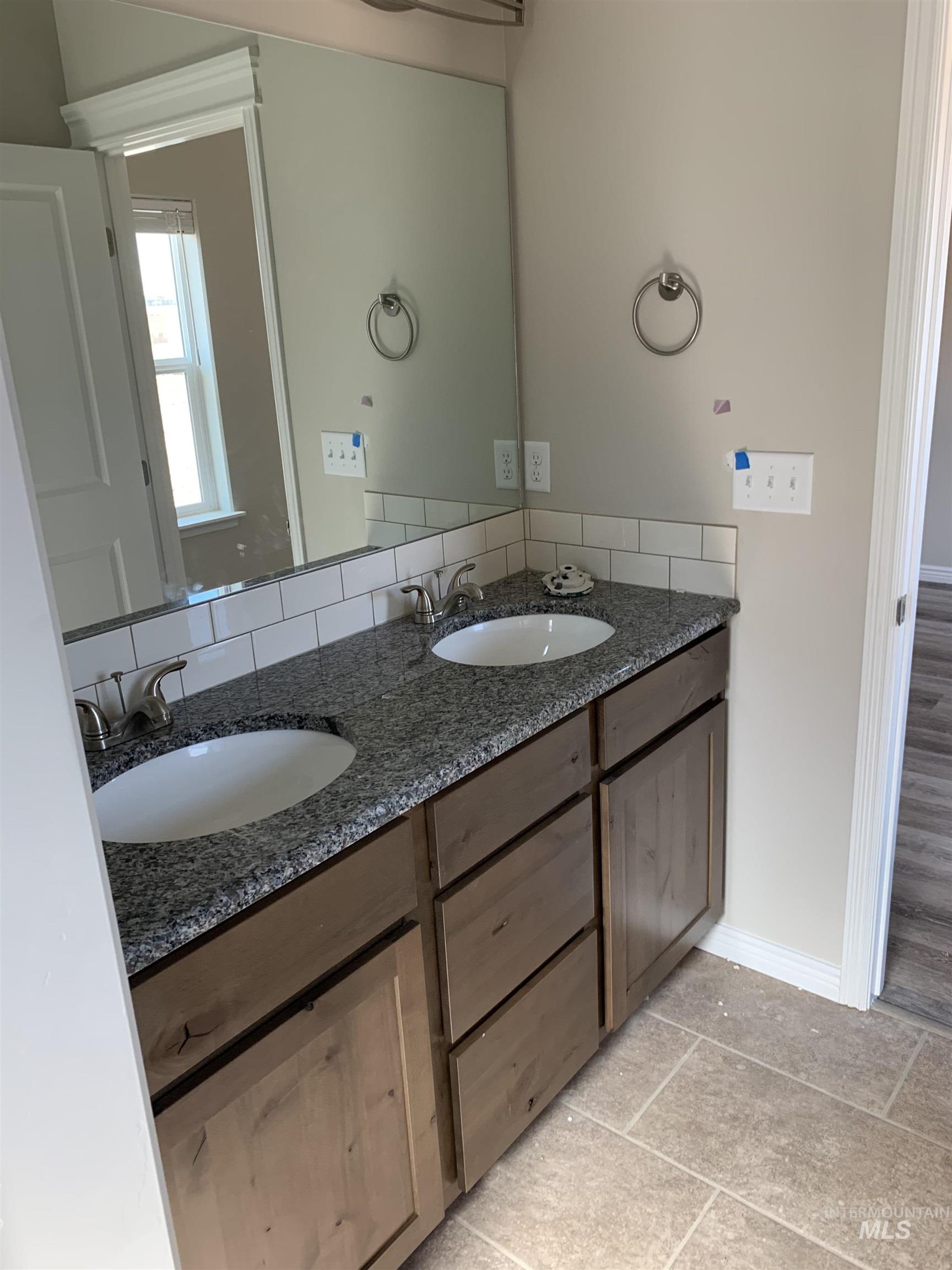 Bathroom with double vanity and light tile patterned floors