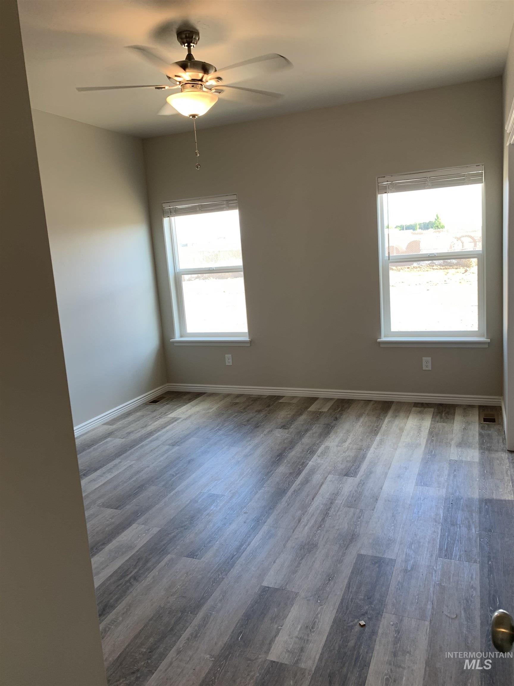 Empty room with light wood finished floors and a ceiling fan