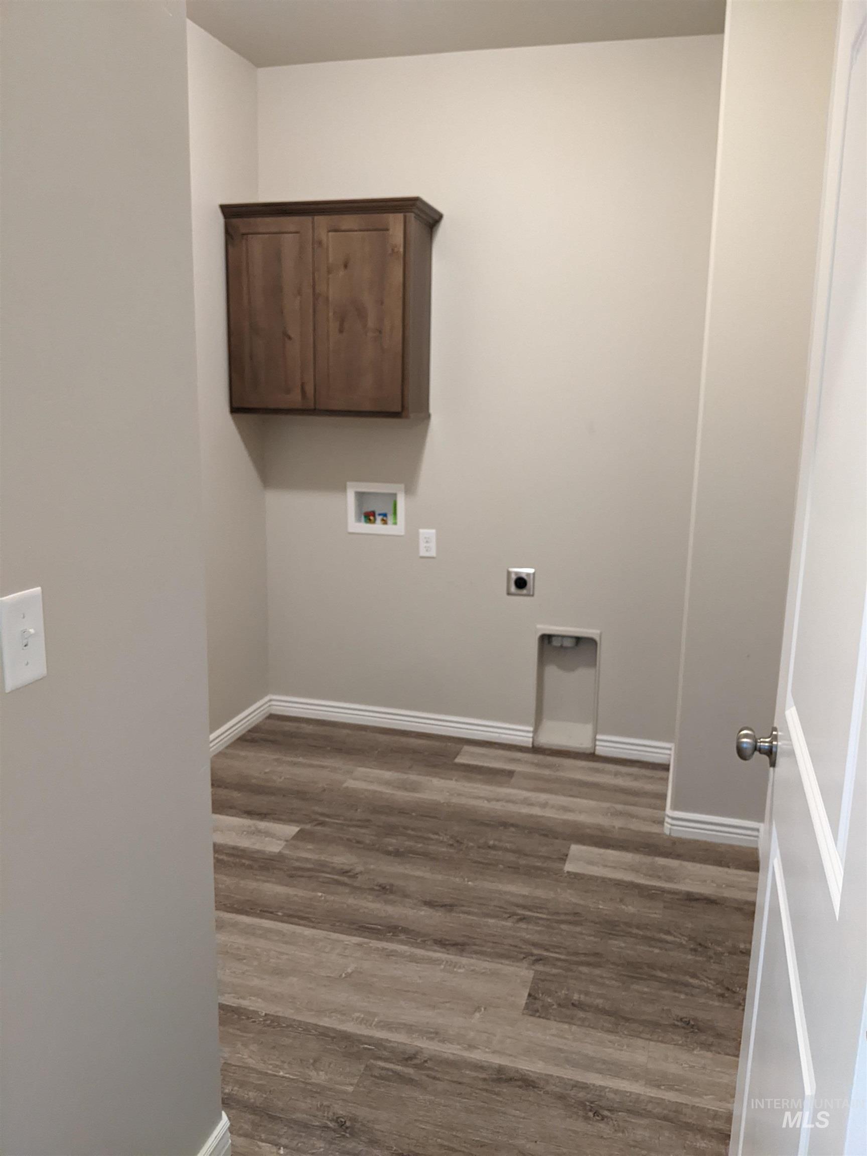 Laundry room featuring light wood-style floors, electric dryer hookup, washer hookup, and cabinet space