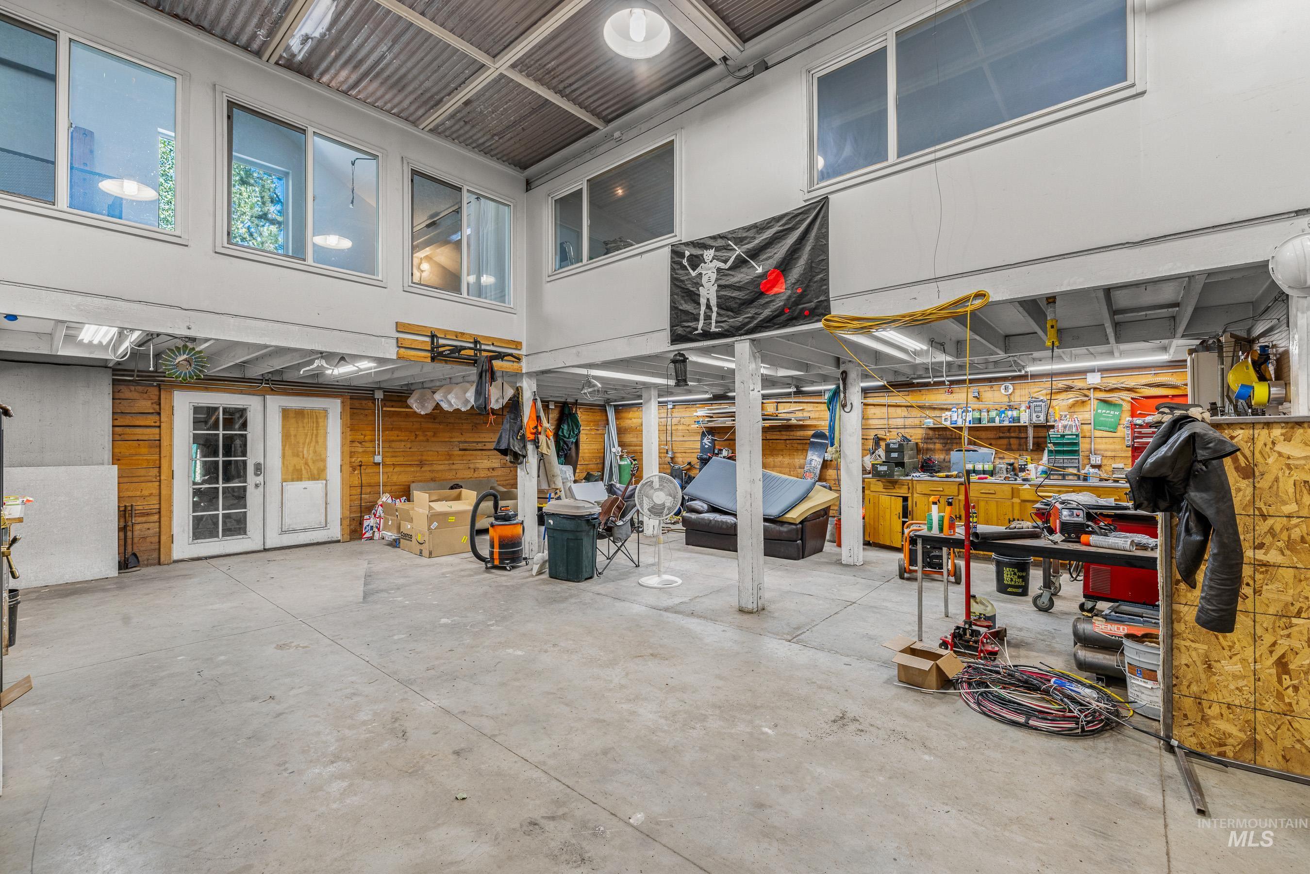 Miscellaneous room featuring concrete flooring, a workshop area, wooden walls, and a high ceiling