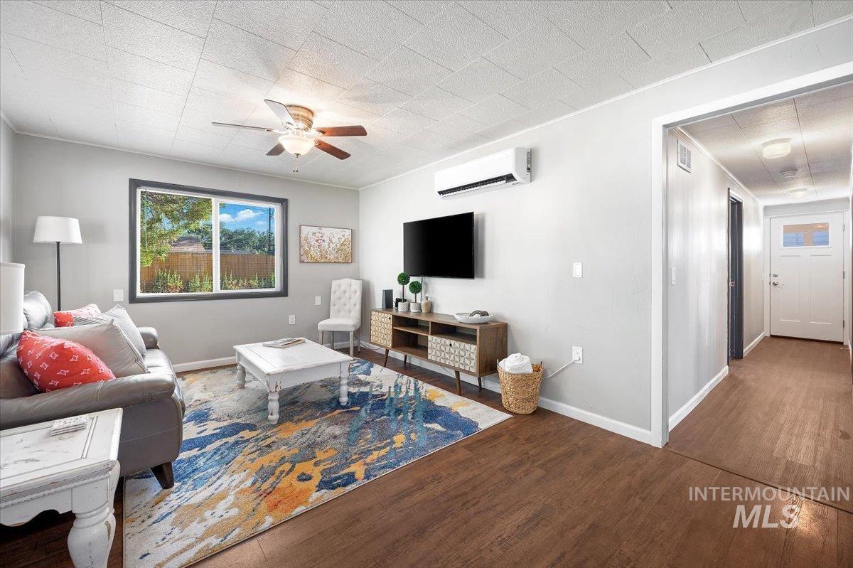 Living area featuring wood finished floors, ceiling fan, and a wall mounted AC