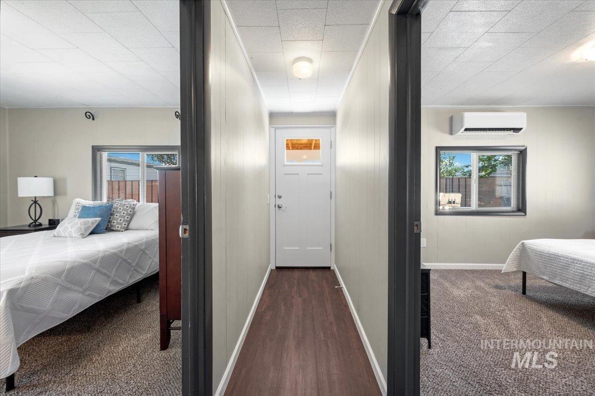 Hallway with dark colored carpet and a wall unit AC