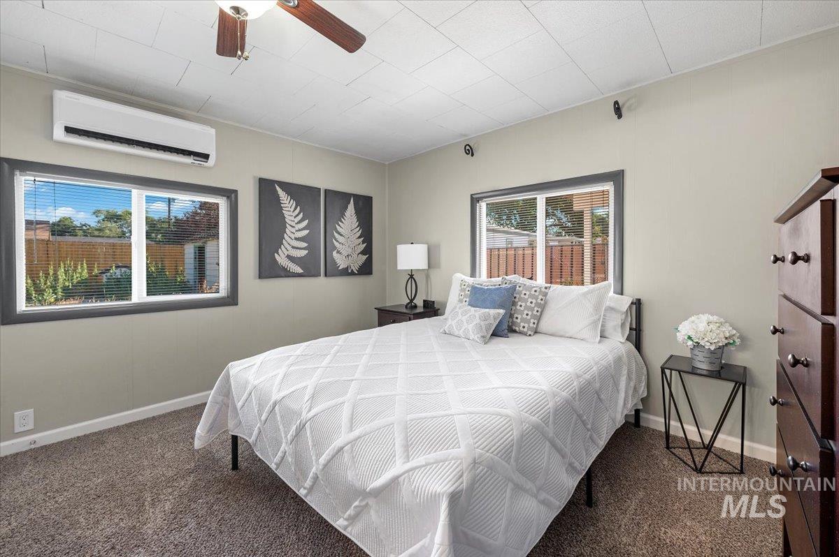 Bedroom with a wall unit AC, ceiling fan, and carpet