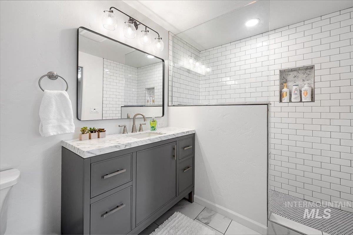 Bathroom with vanity, walk in shower, and light marble finish flooring