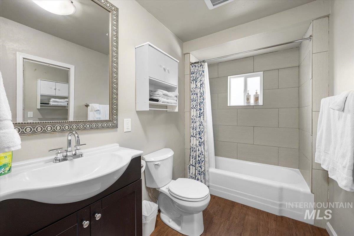 Full bath with dark wood finished floors, vanity, and shower / bath combo