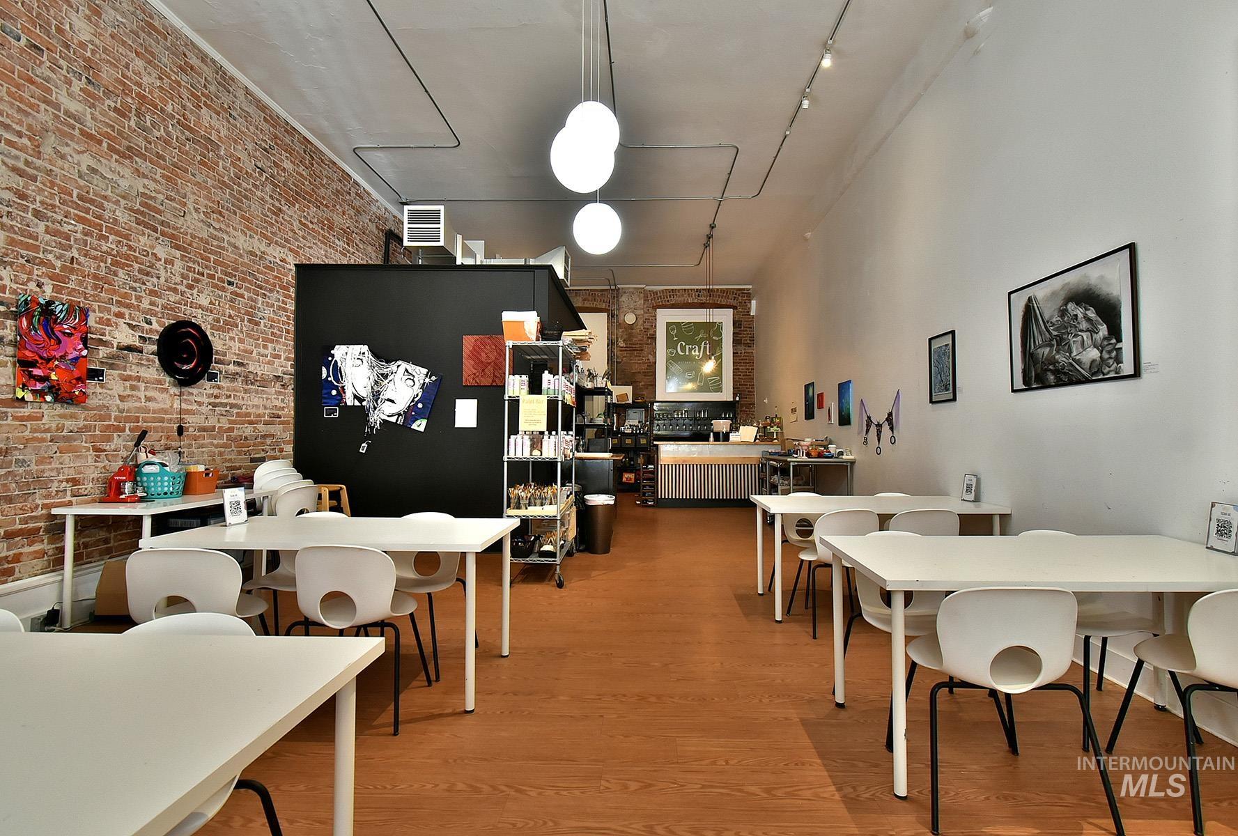 Dining space featuring brick wall, light wood-style floors, attic access, and rail lighting