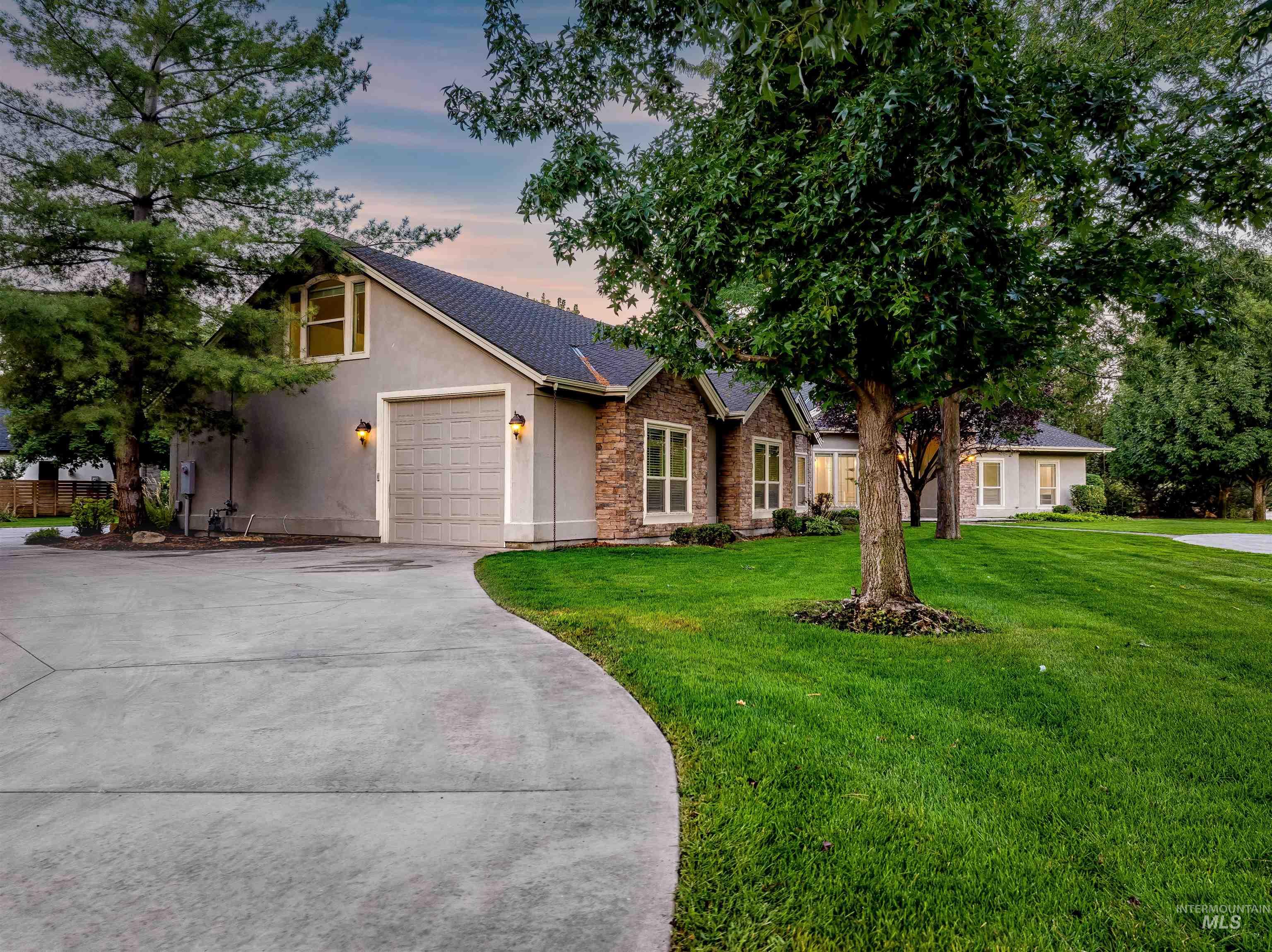 Ranch-style house featuring a front yard, stucco siding, driveway, a shingled roof, and a garage