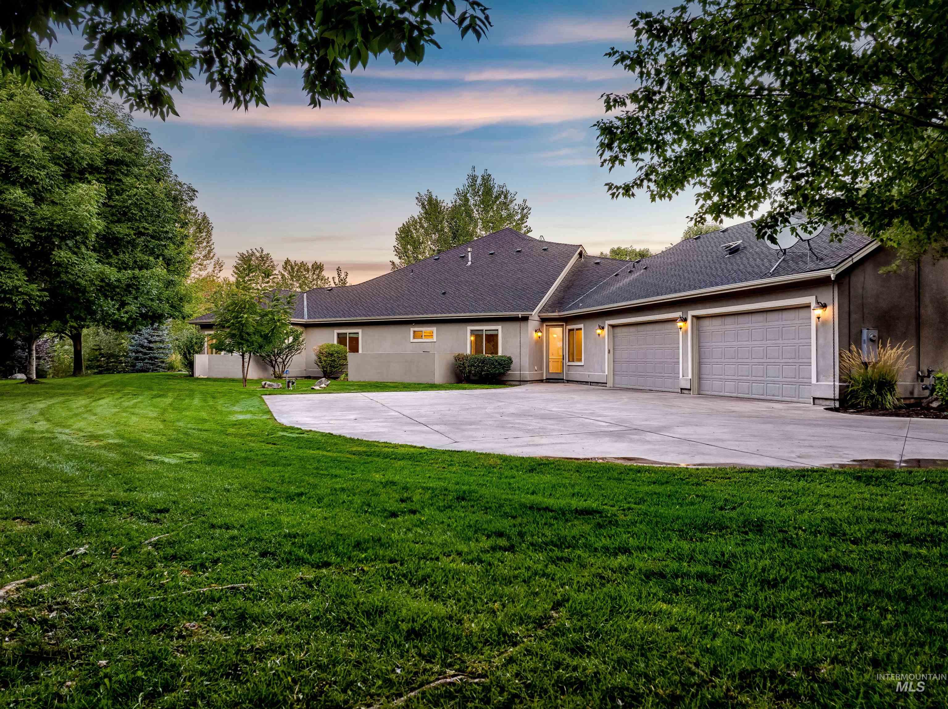 View of front of property with concrete driveway, a lawn, a garage, and roof with shingles