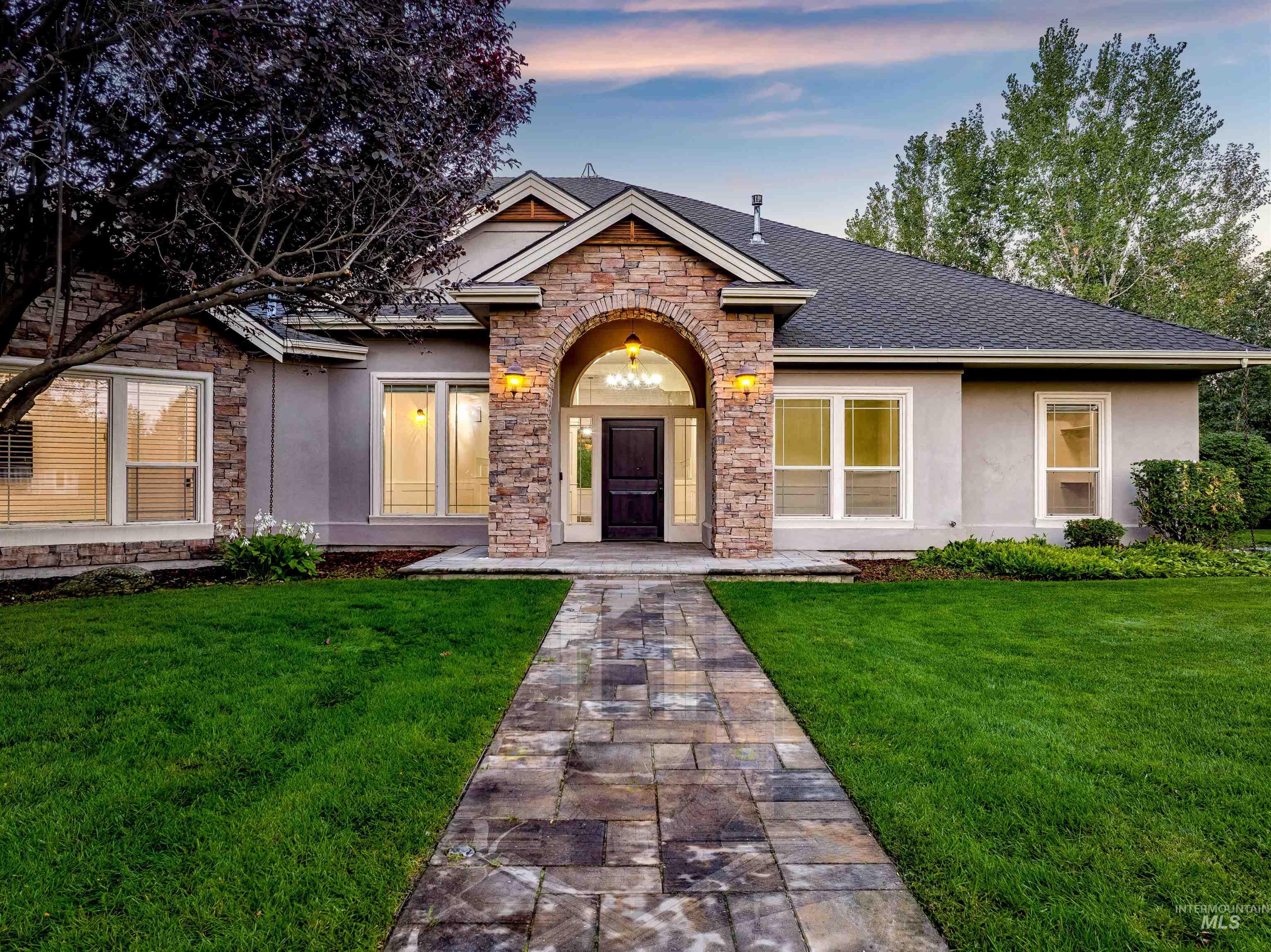 View of front of house with stucco siding, a front lawn, stone siding, and a shingled roof