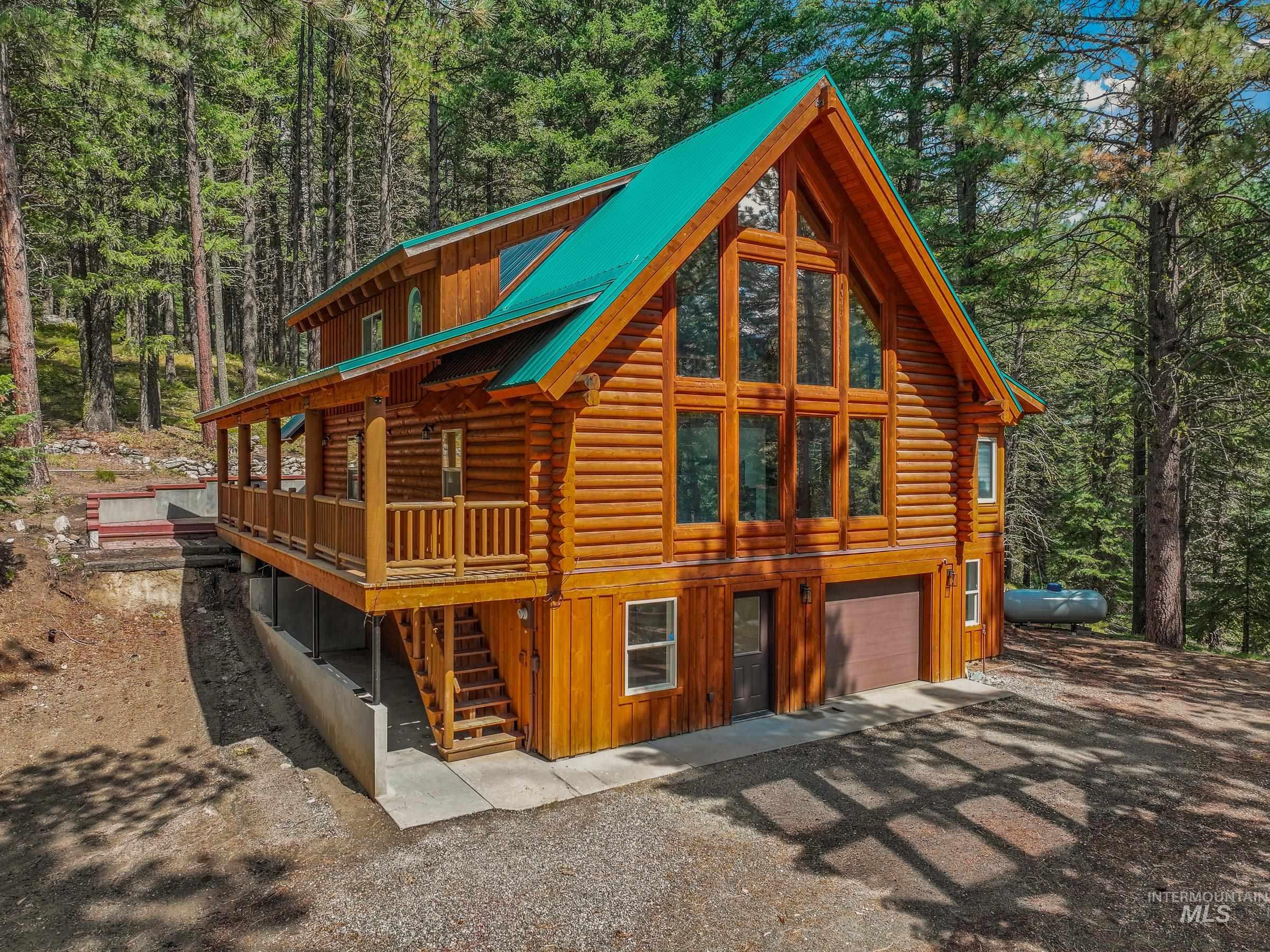 View of front facade featuring log siding, stairs, a metal roof, board and batten siding, and a wooded view