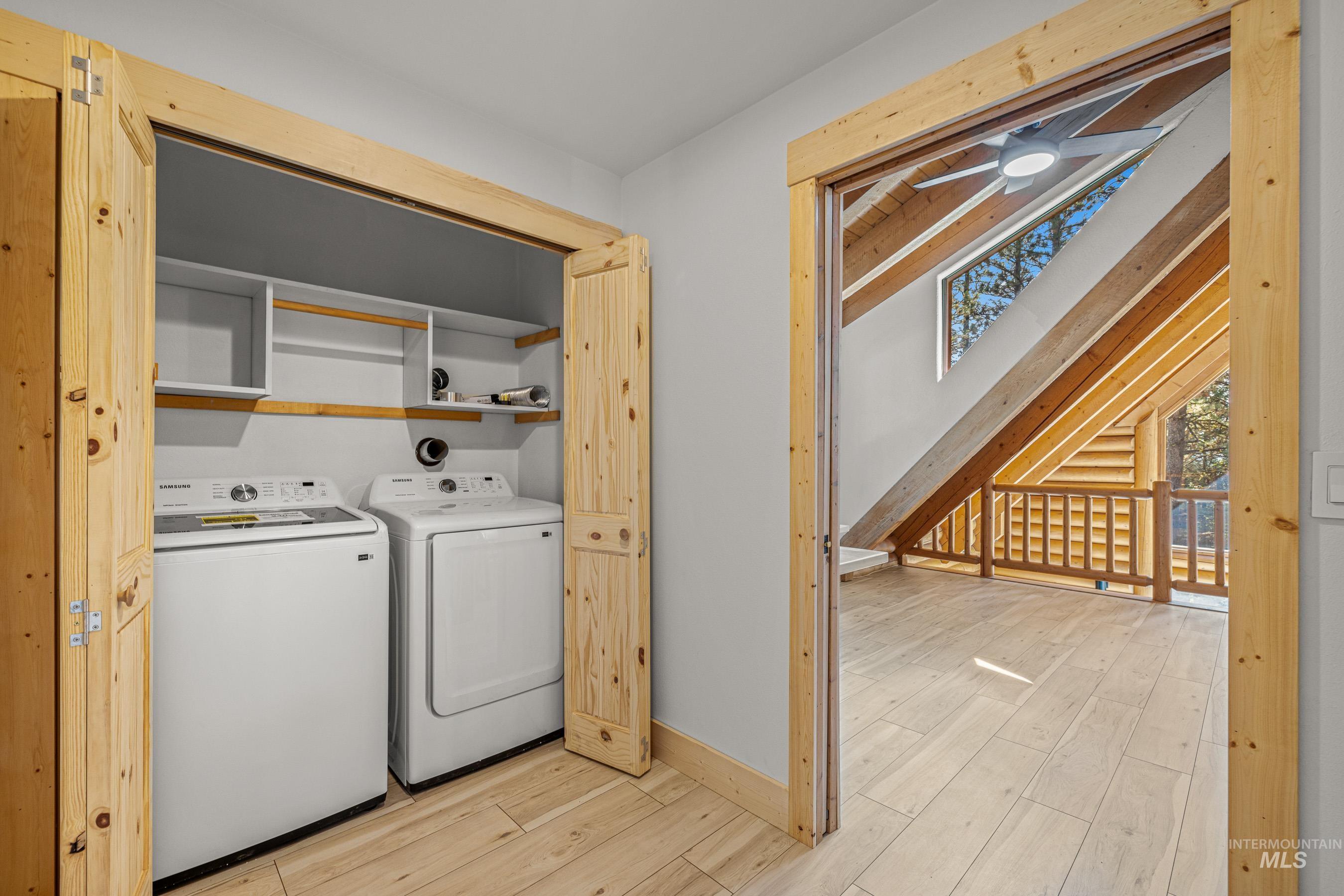 Laundry room with light wood-style floors, washing machine and clothes dryer, and ceiling fan