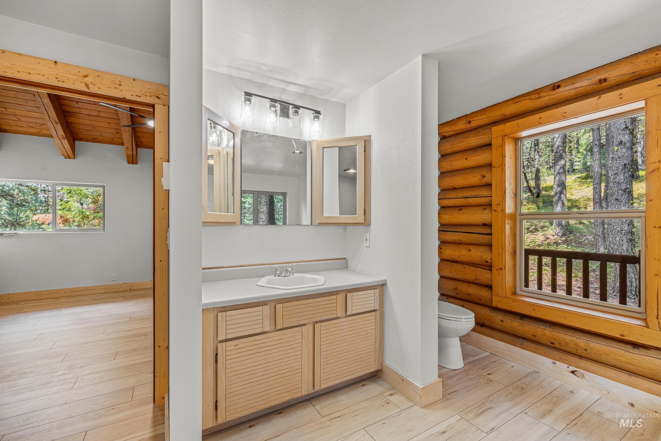 Bathroom featuring light wood-style floors, vanity, and log walls