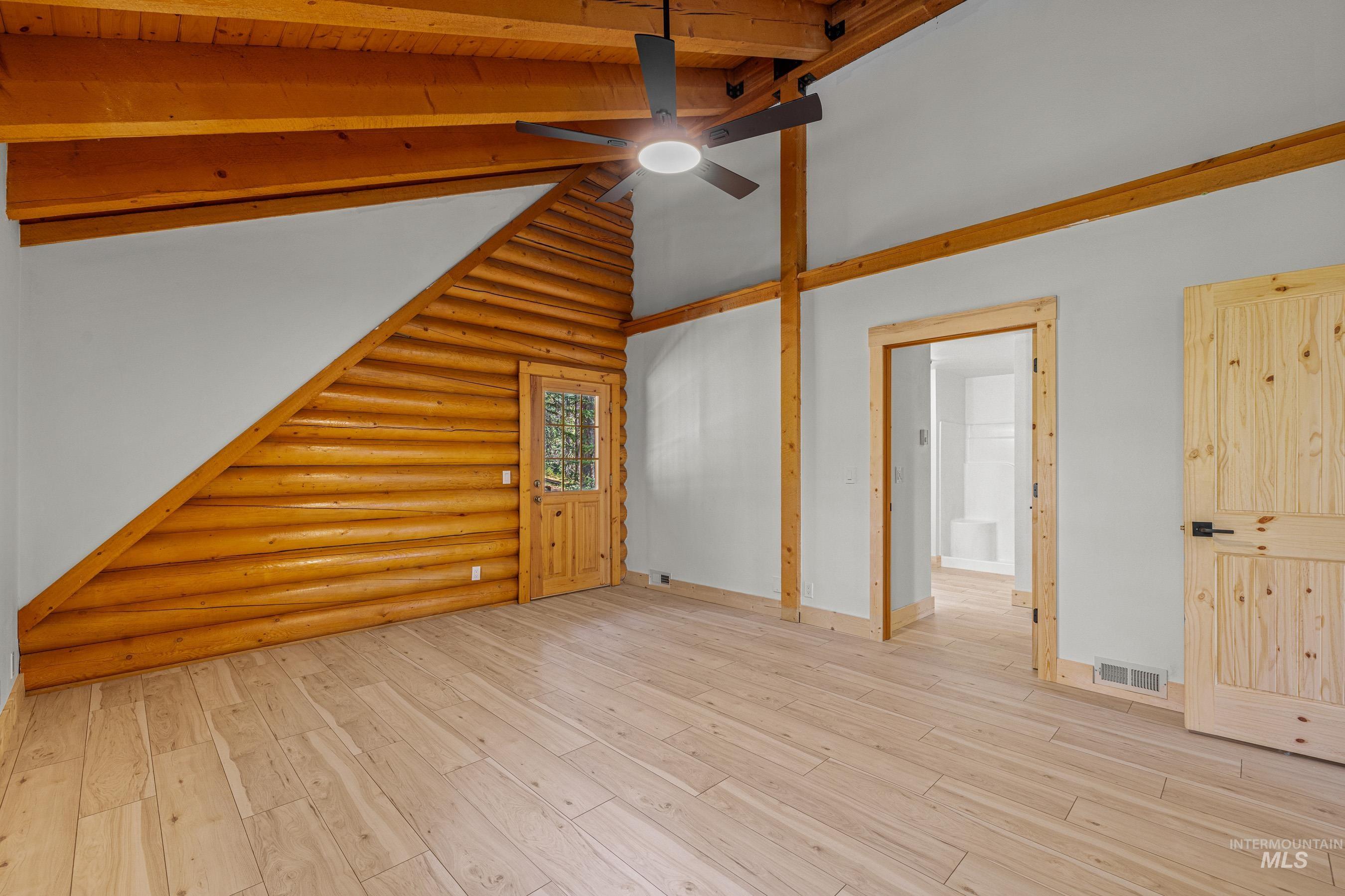 Bonus room with high vaulted ceiling, log walls, hardwood / wood-style flooring, and beam ceiling