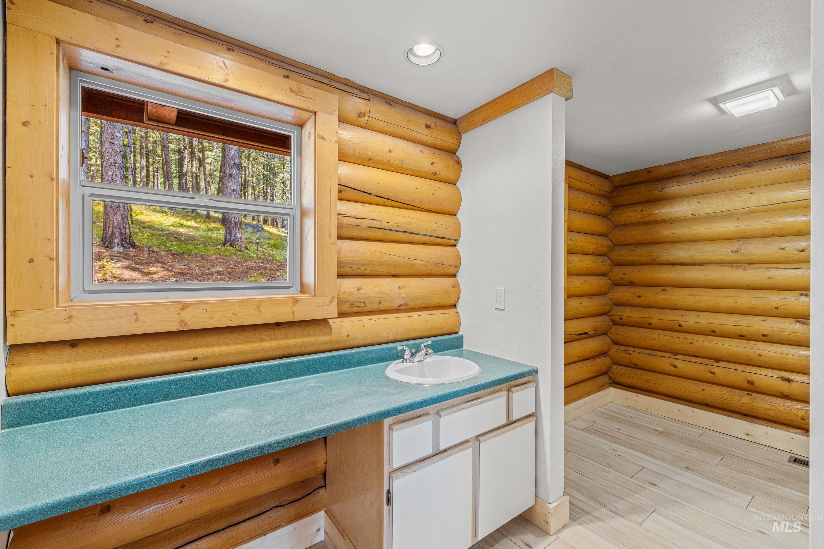 Bathroom featuring vanity, rustic walls, light wood-style floors, and recessed lighting
