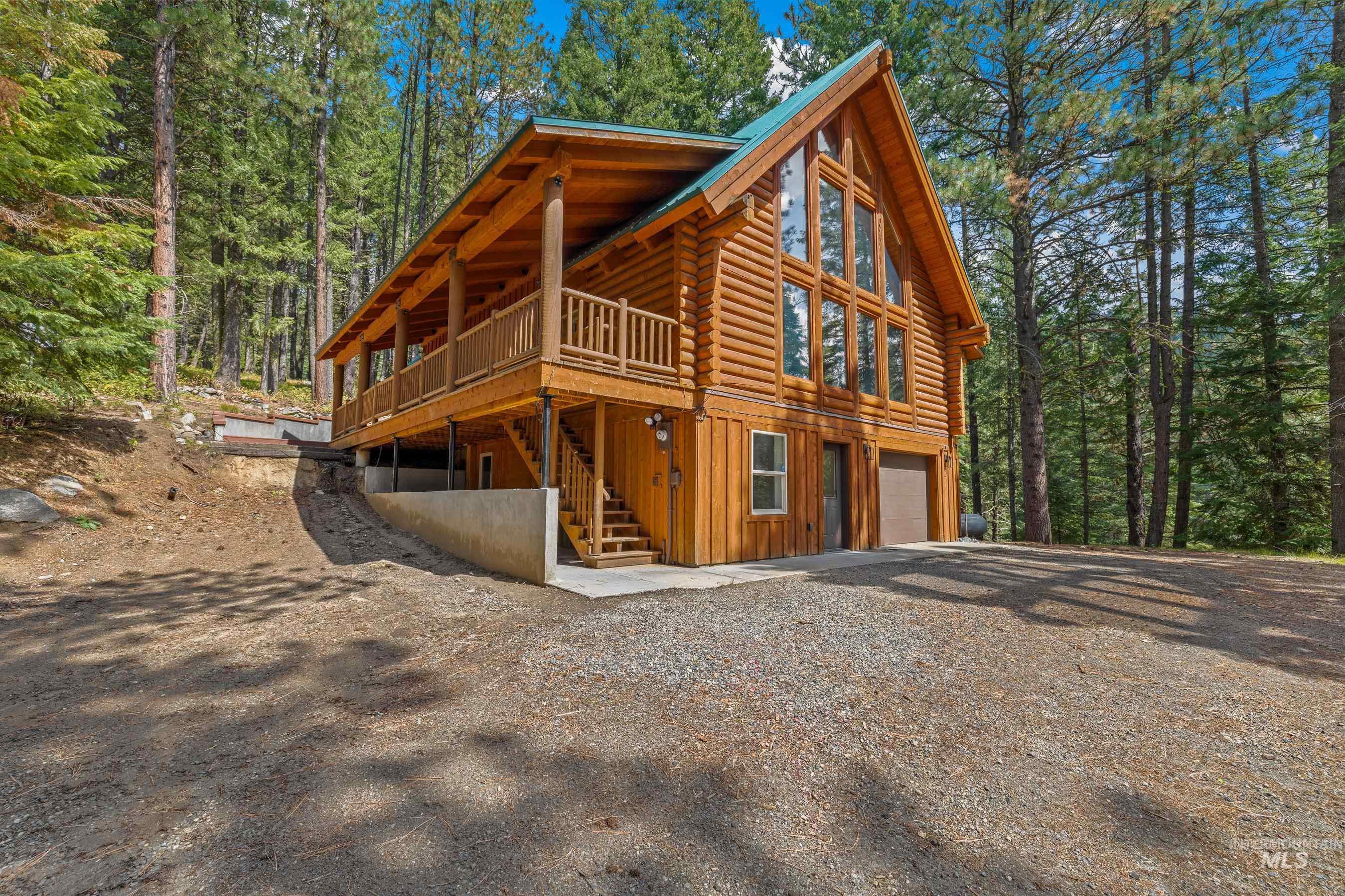 View of side of property with stairs, log exterior, board and batten siding, a garage, and driveway