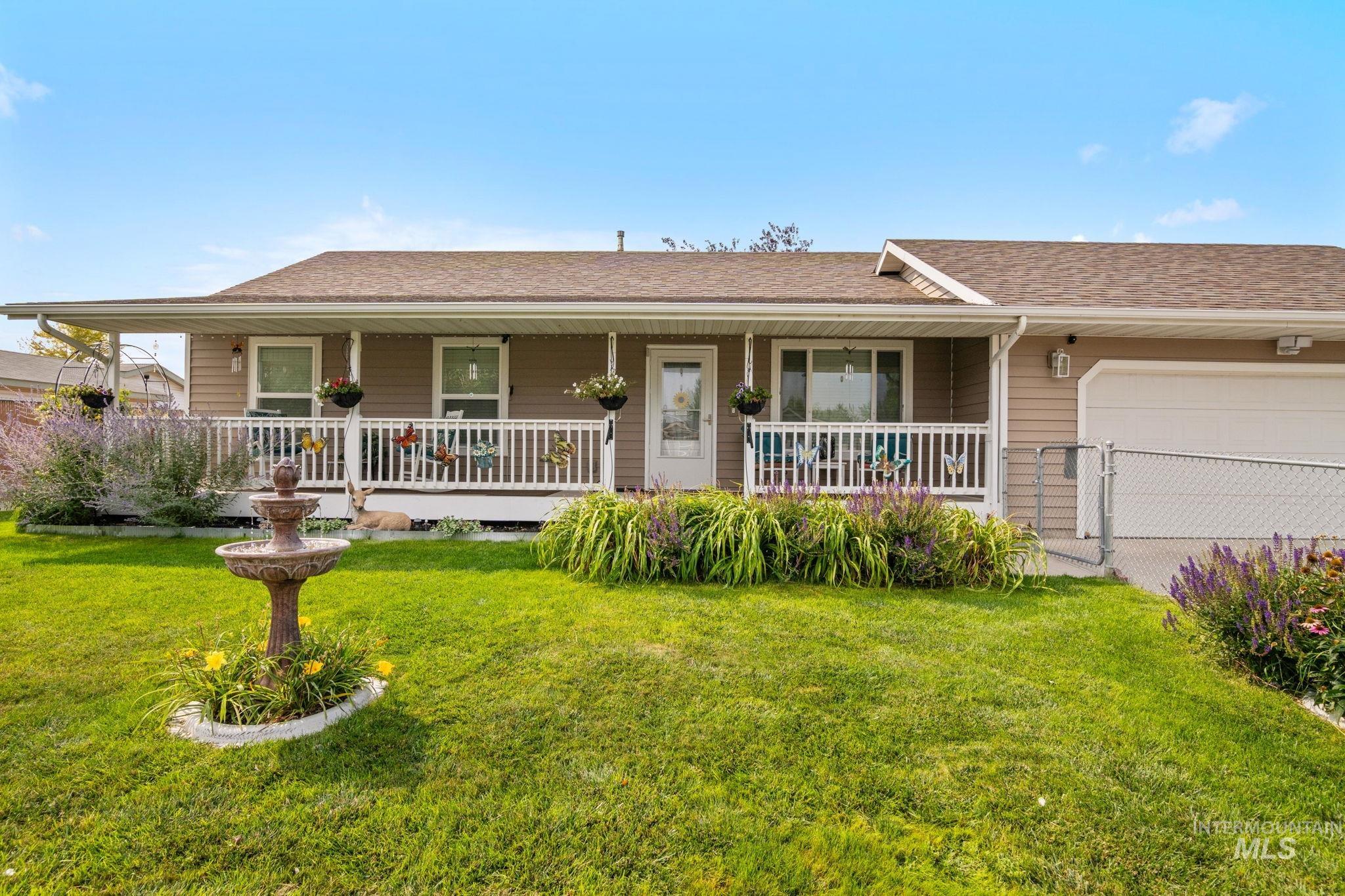 Single story home featuring covered porch, a shingled roof, and an attached garage