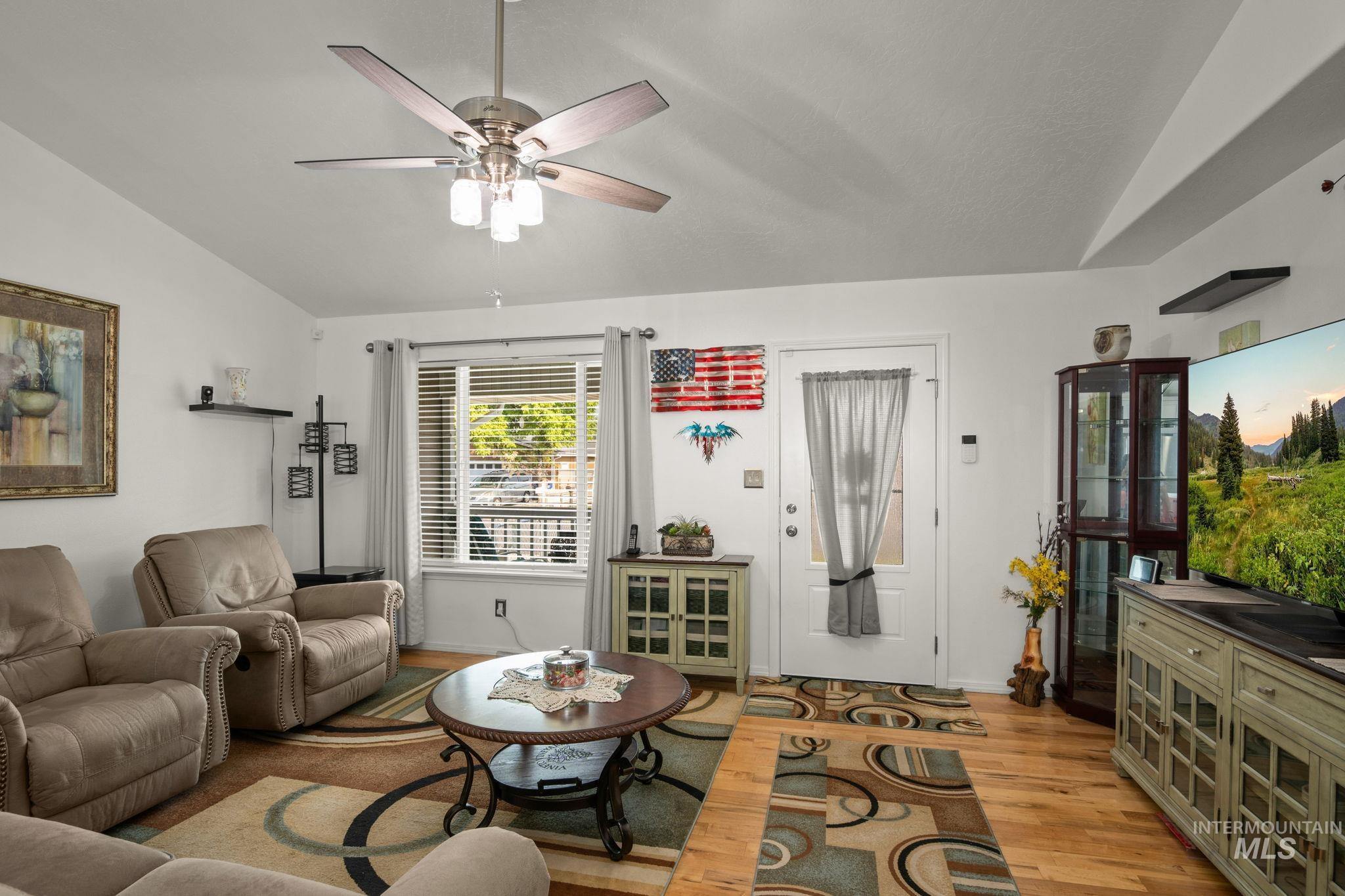 Living room featuring lofted ceiling, light wood-style flooring, and ceiling fan