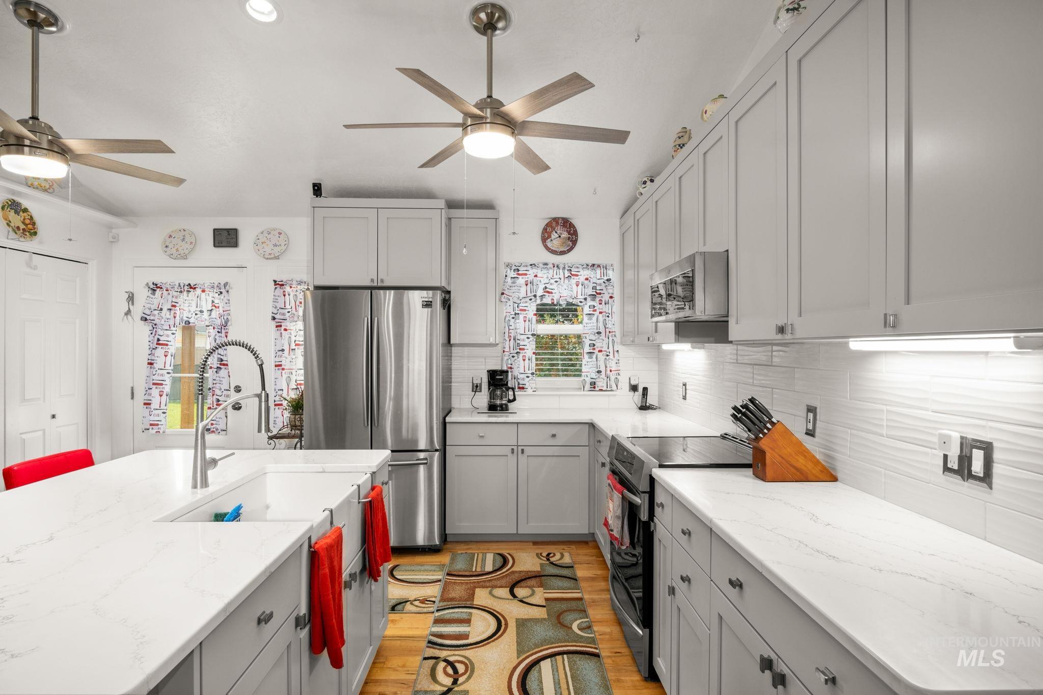 Kitchen featuring stainless steel appliances, light wood-type flooring, decorative backsplash, light stone countertops, and recessed lighting