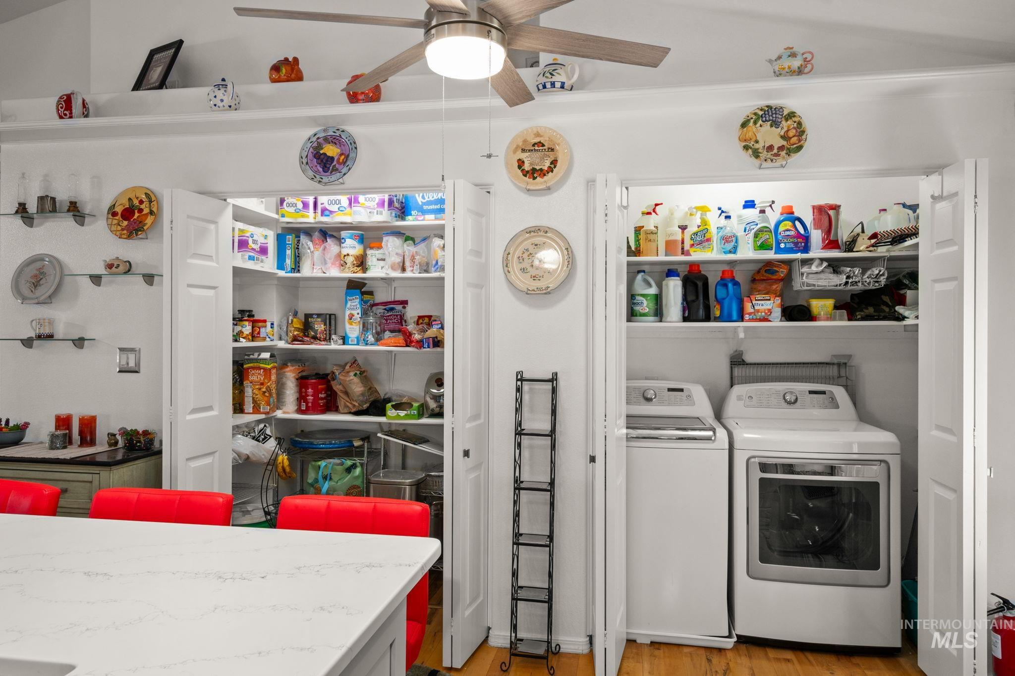 Laundry area with light wood-style flooring, washing machine and clothes dryer, and ceiling fan