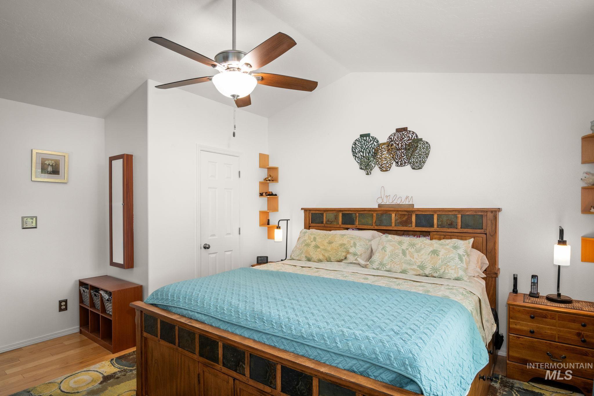 Bedroom with lofted ceiling, light wood-style flooring, and a ceiling fan