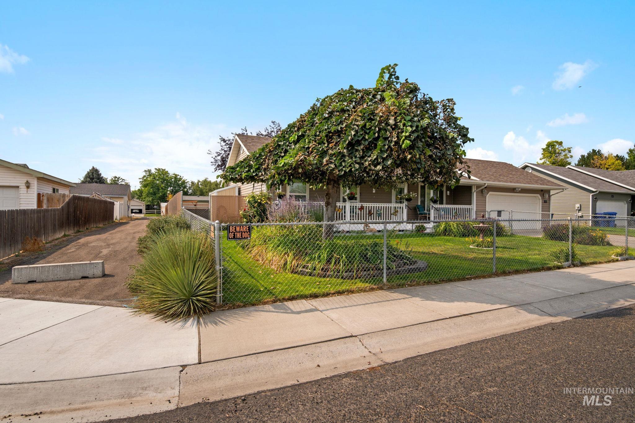 Obstructed view of property with a fenced front yard, an attached garage, covered porch, and driveway