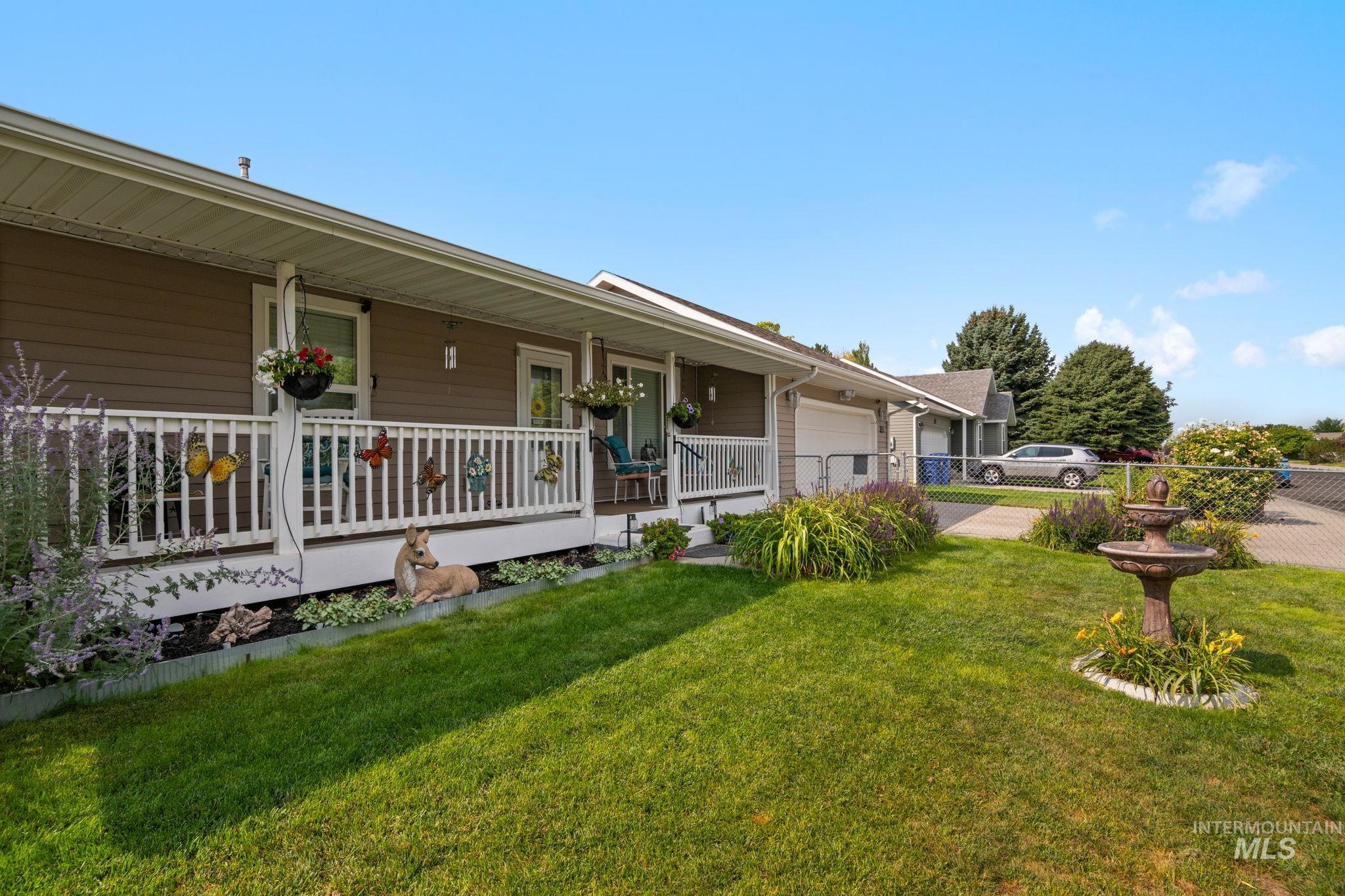 View of front facade featuring a porch, a front yard, a garage, and driveway