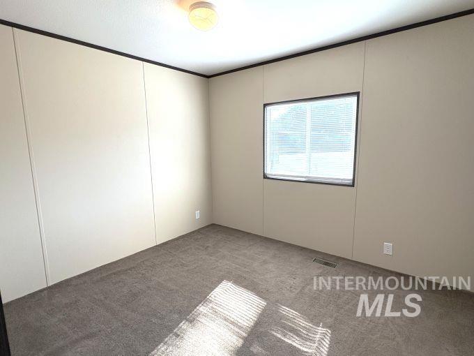 Unfurnished room featuring carpet and crown molding