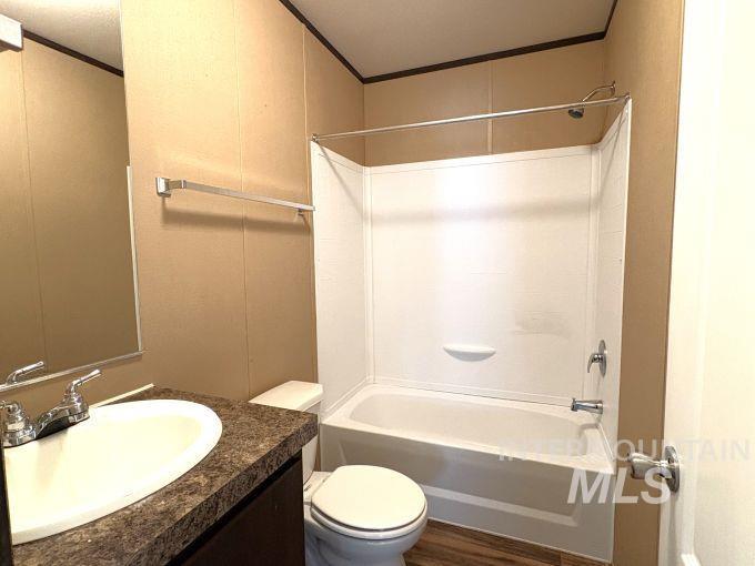 Full bath featuring shower / tub combination, vanity, crown molding, and dark wood-style floors