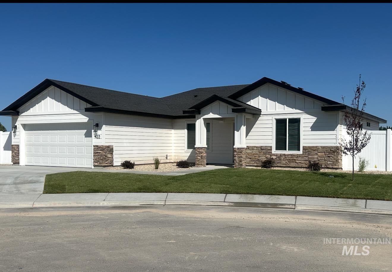 View of front facade featuring stone siding, board and batten siding, driveway, and a garage