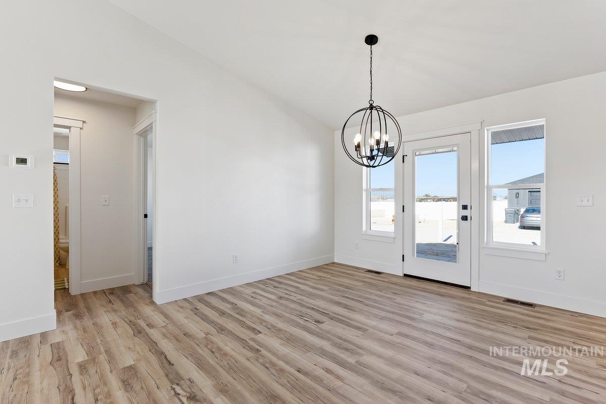 Unfurnished dining area featuring light wood-style flooring and a chandelier