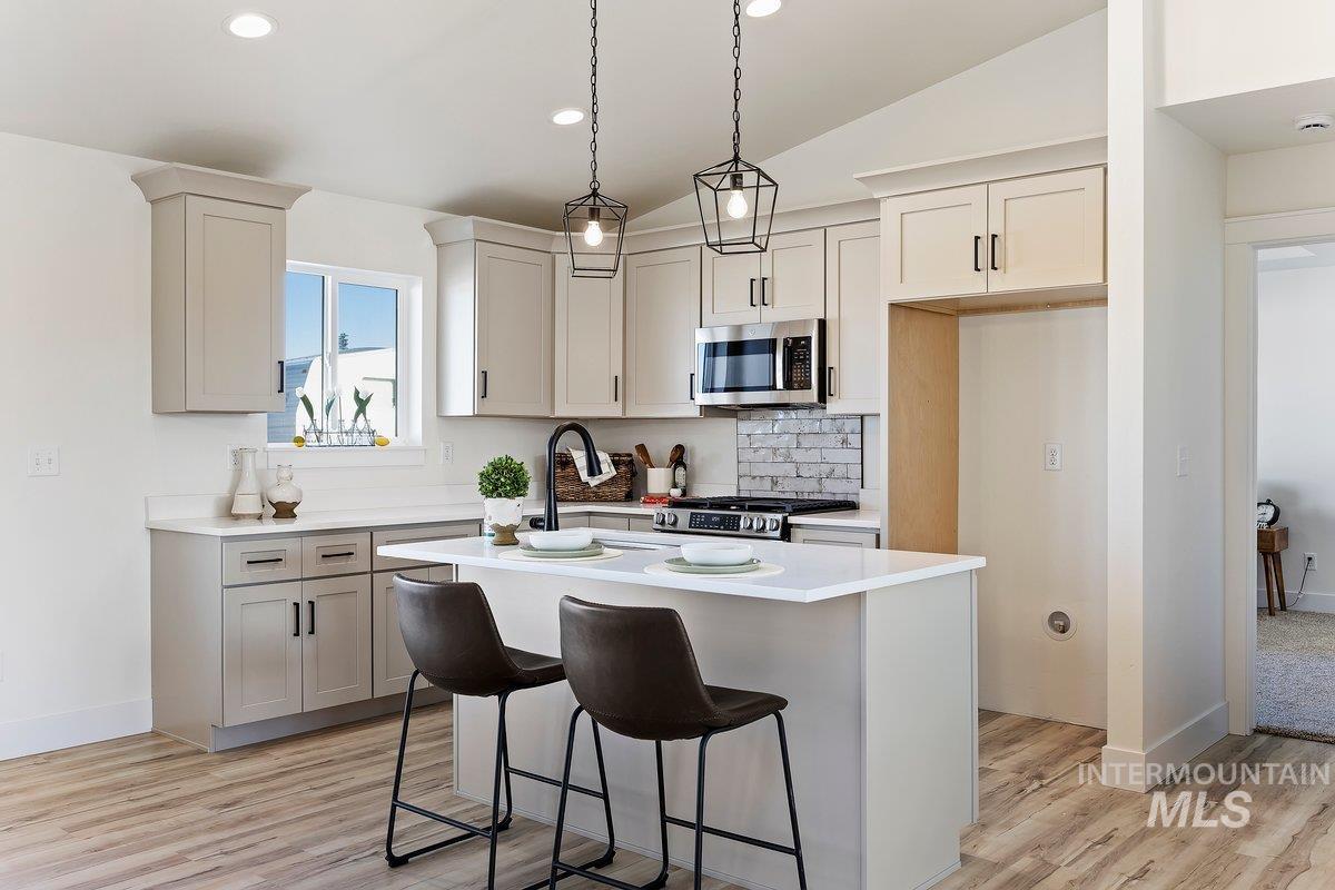 Kitchen with a kitchen bar, a kitchen island, appliances with stainless steel finishes, hanging light fixtures, and recessed lighting