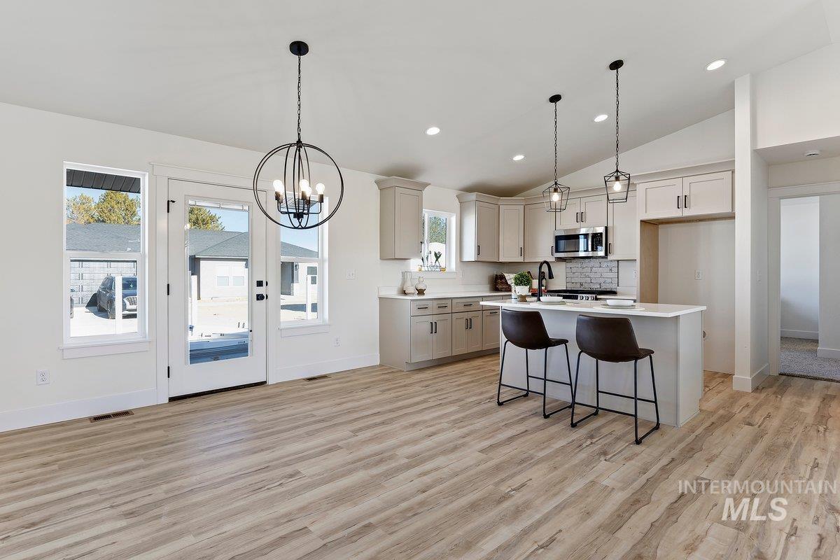 Kitchen with pendant lighting, a kitchen bar, light wood-type flooring, backsplash, and recessed lighting