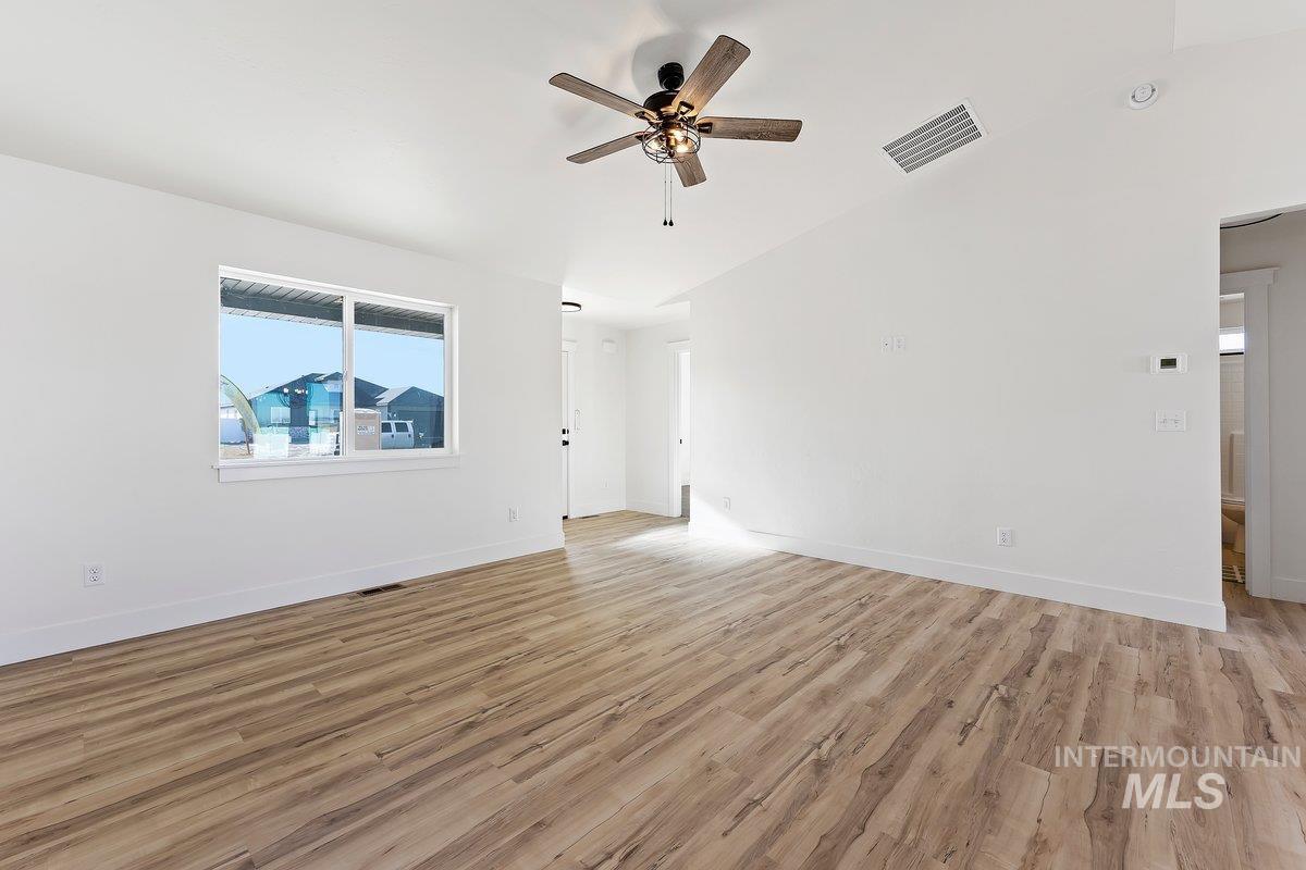 Spare room featuring light wood-style flooring, lofted ceiling, and ceiling fan