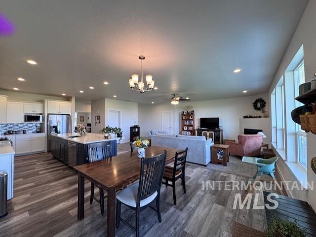 Dining area with dark wood finished floors, a chandelier, recessed lighting, and ceiling fan