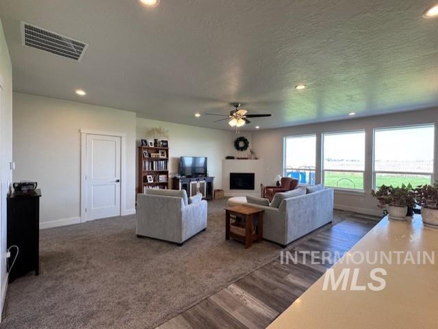 Living area with recessed lighting, a fireplace, dark wood finished floors, and a ceiling fan