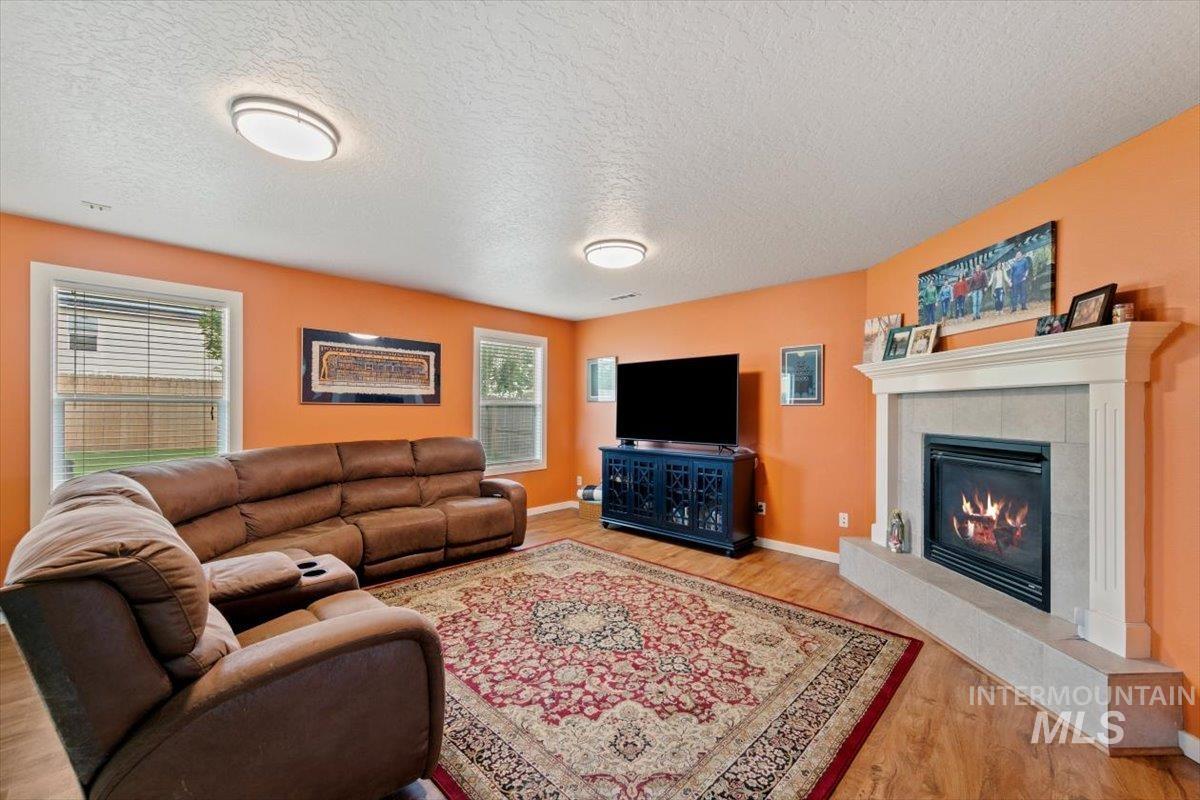 Living room featuring light wood-type flooring, a fireplace, and a textured ceiling