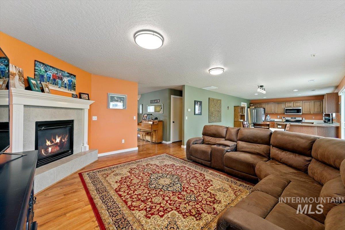 Living area featuring light wood-style flooring, a fireplace, and a textured ceiling